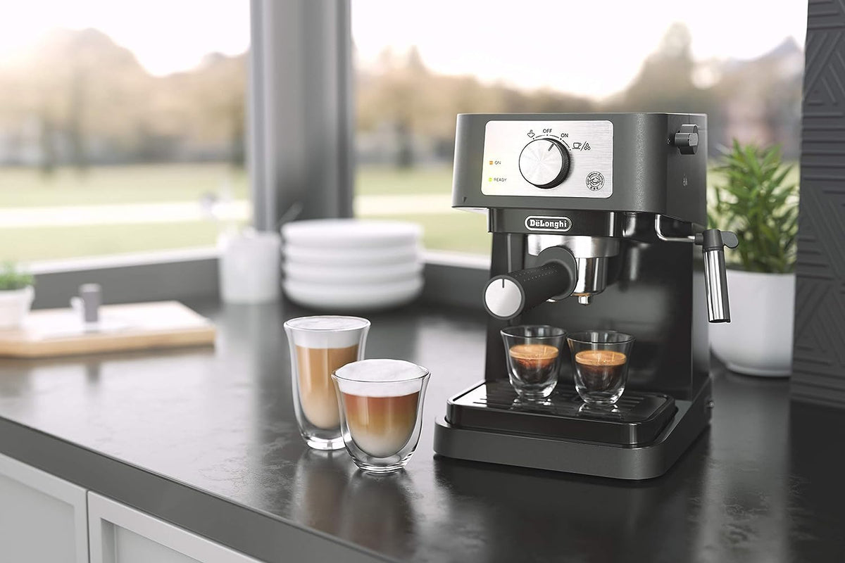 Black espresso machine dispensing coffee into two glass cups on counter