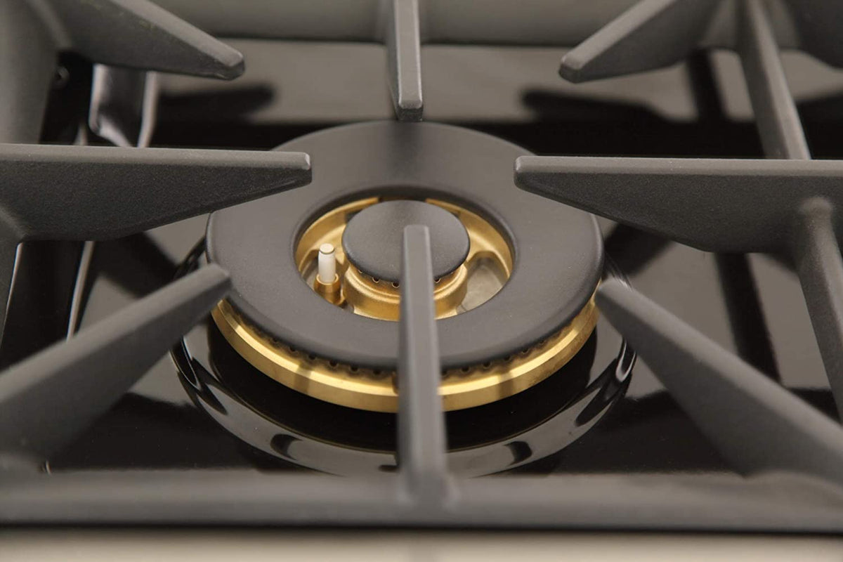Gas cooktop burner close-up with black grate and gold-colored burner cap