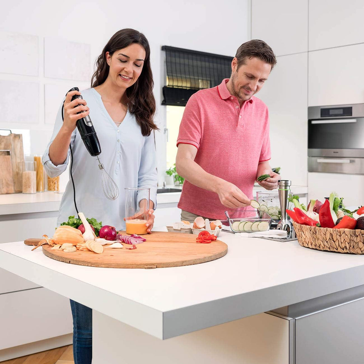 Stainless steel Braun hand blender with whisk attachment, held above a mixing bowl