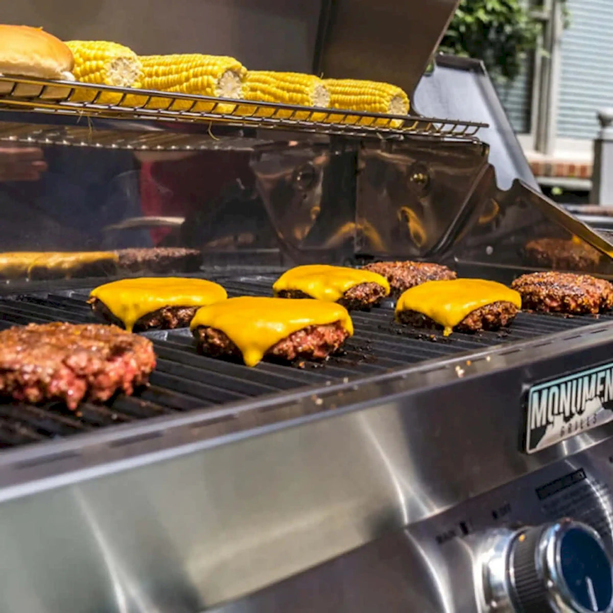 Stainless steel propane gas grill with burgers cooking on the grates