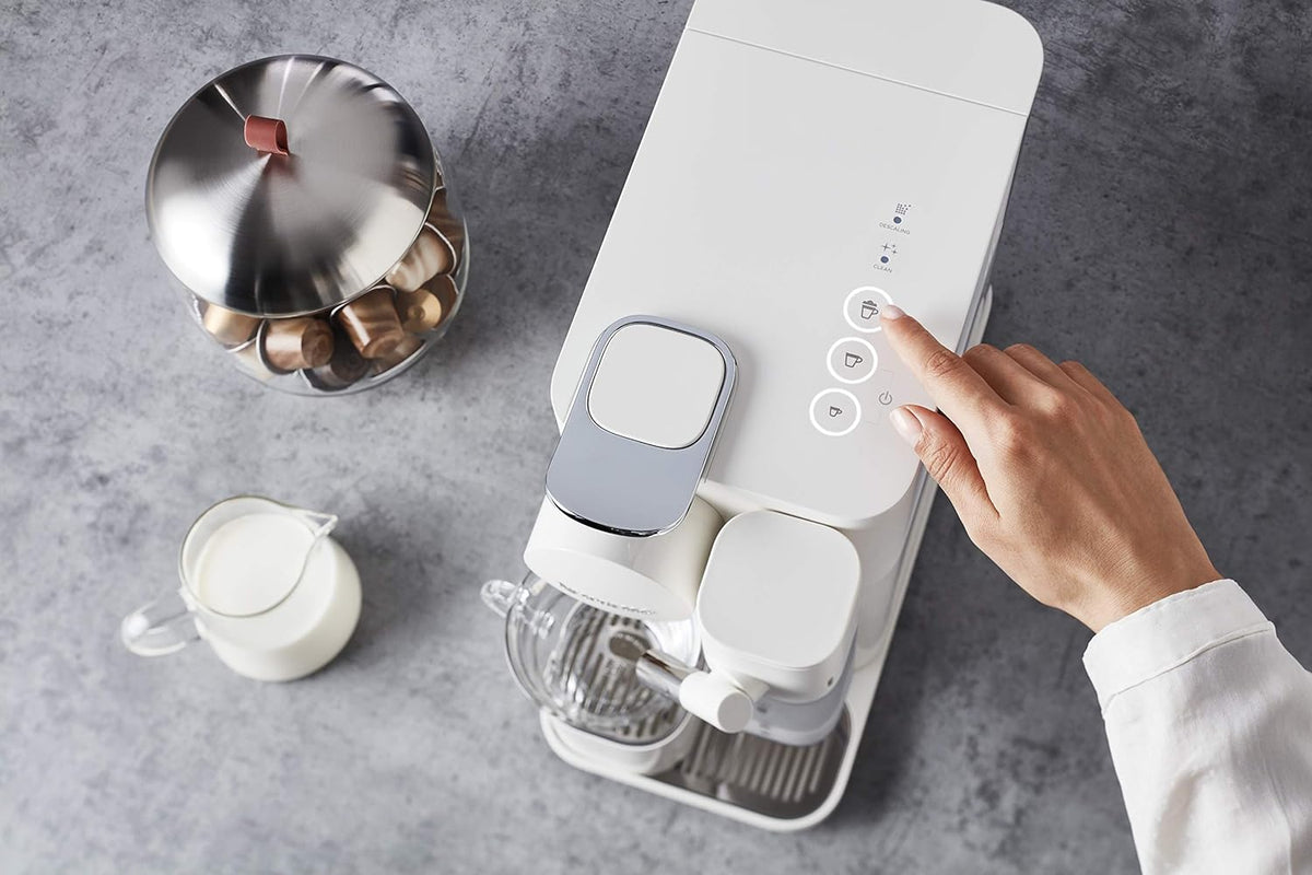 White countertop coffee machine with touch controls and milk container, hand adjusting