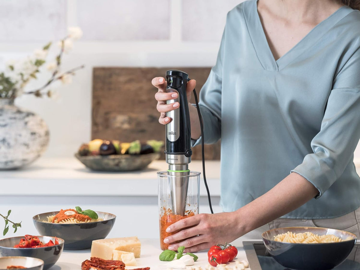 Braun stainless steel hand blender blending ingredients in a clear container