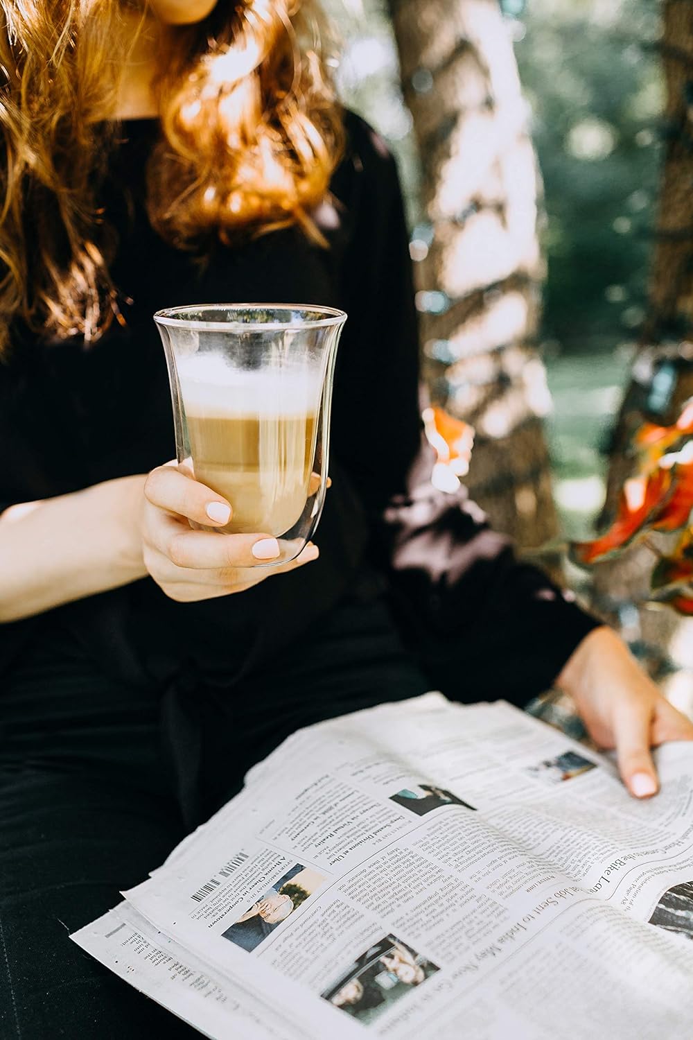 Latte macchiato glass with layered coffee and crema foam, held in hand, clear