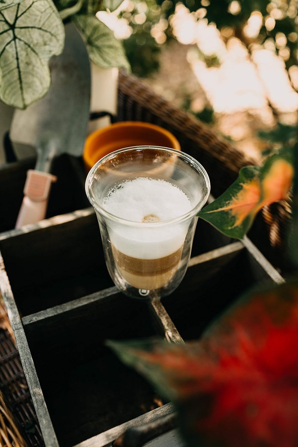 Clear double wall latte macchiato glass with coffee layer and foam, on table