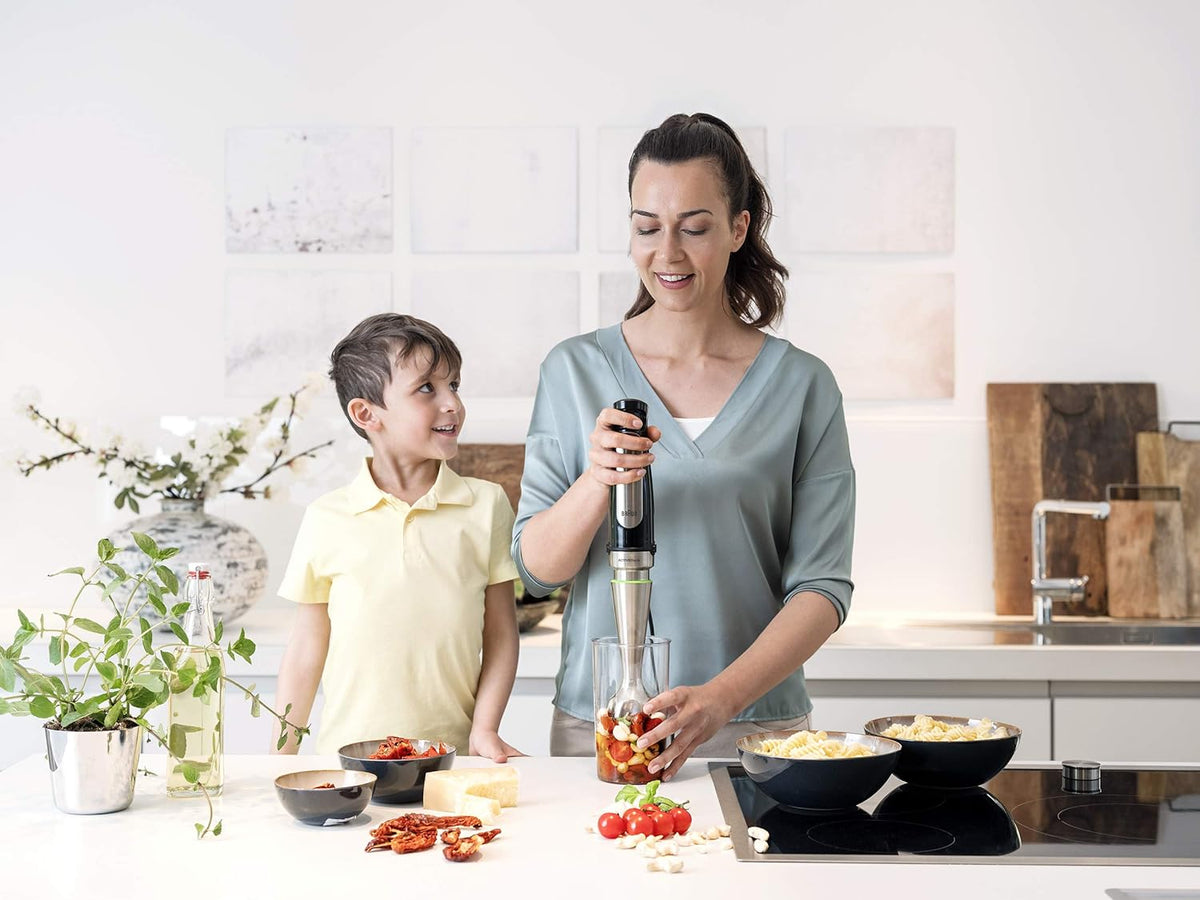 Braun stainless steel hand blender in use for chopping vegetables over a pan