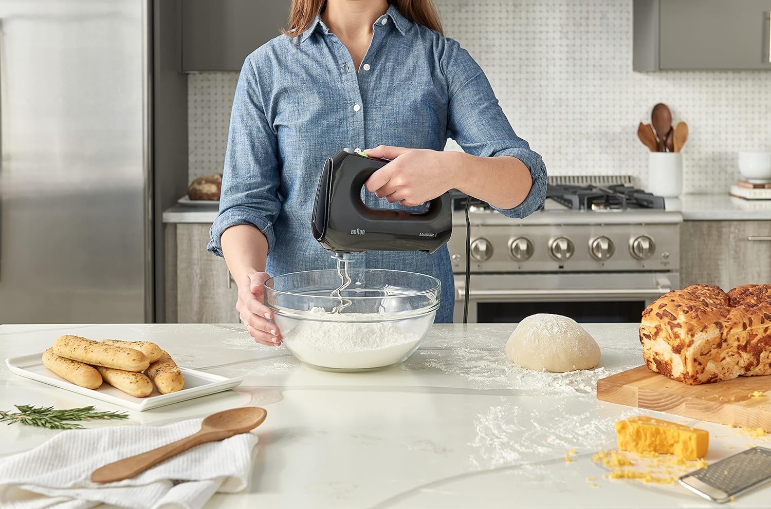 Woman using a black hand mixer while preparing batter in a mixing bowl