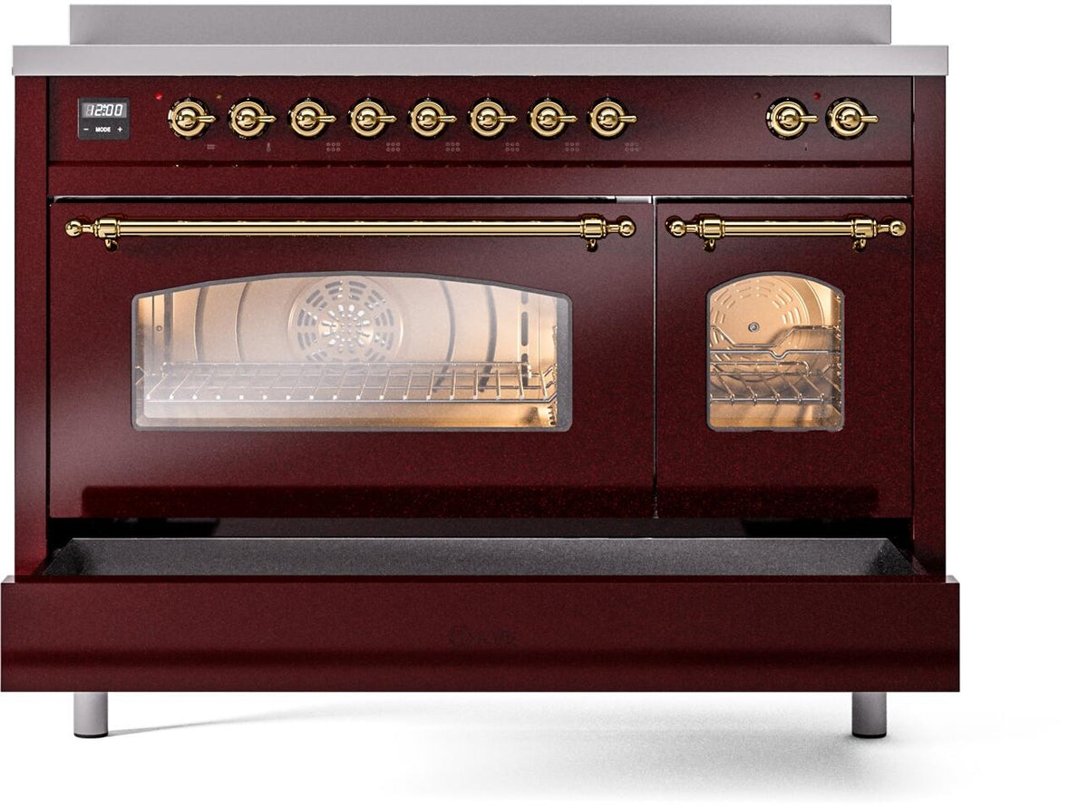 Freestanding electric induction range in burgundy with brass-trimmed handles and lit oven windows