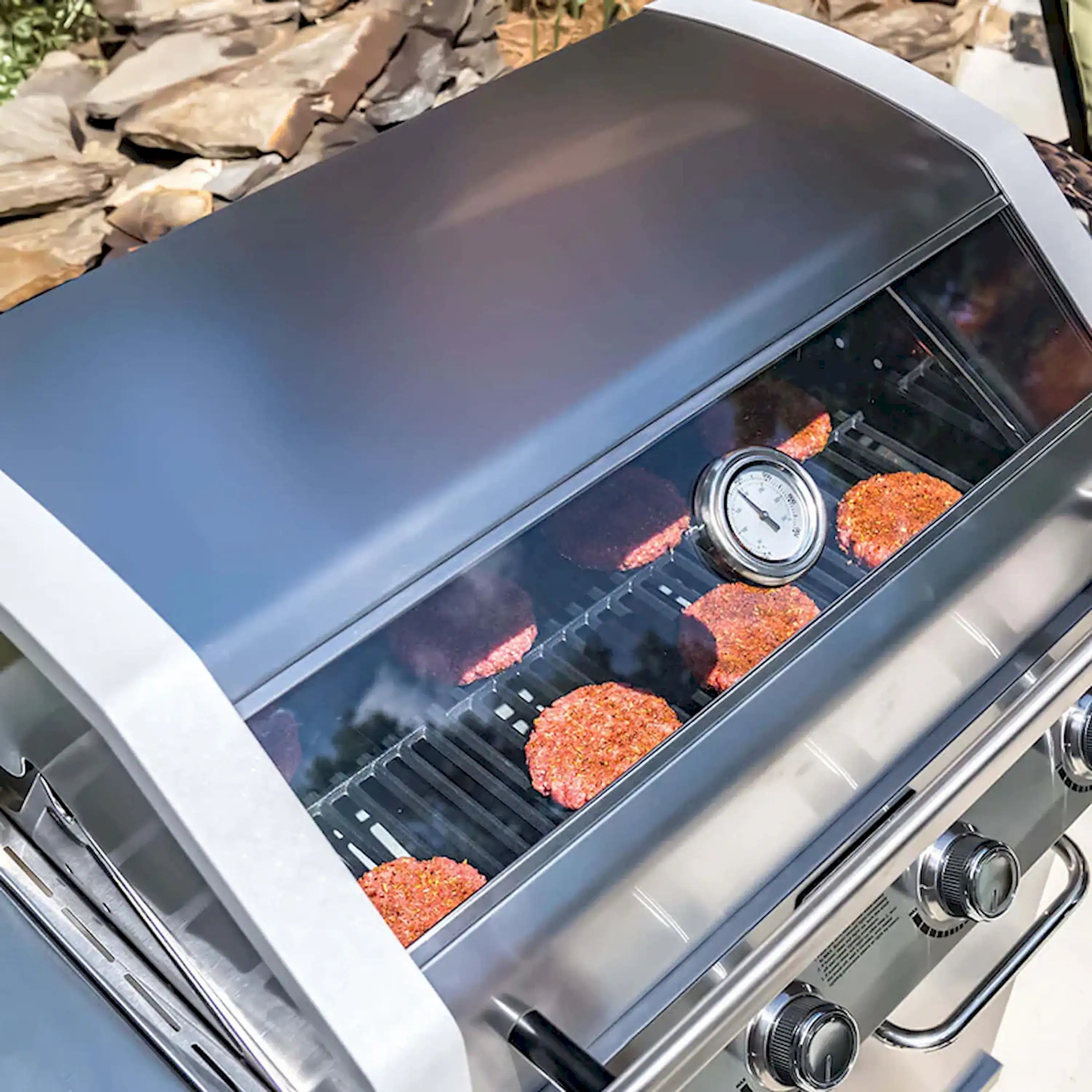 Infrared grill interior with glowing burner tubes and meat filled on grates