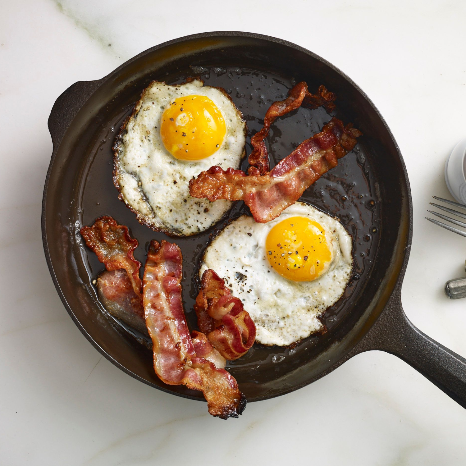 Field Company cast iron skillet with two sunny-side eggs and bacon