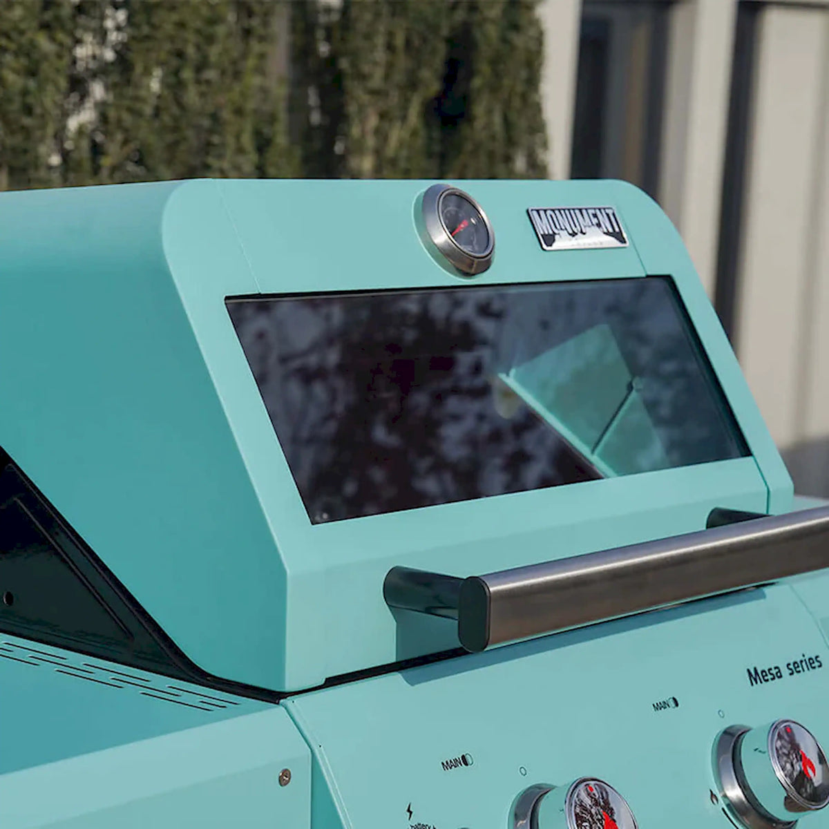 Green grill hood with viewing window and mounted thermometer near the lid front