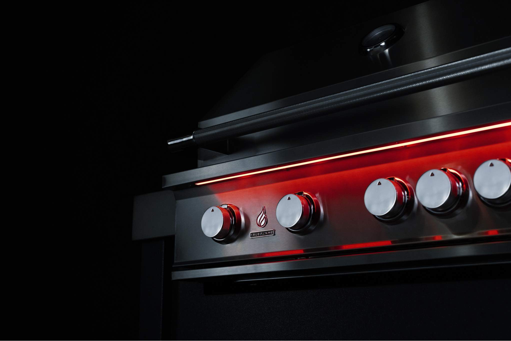 Close-up of stainless steel control knobs with red LED backlighting on propane grill