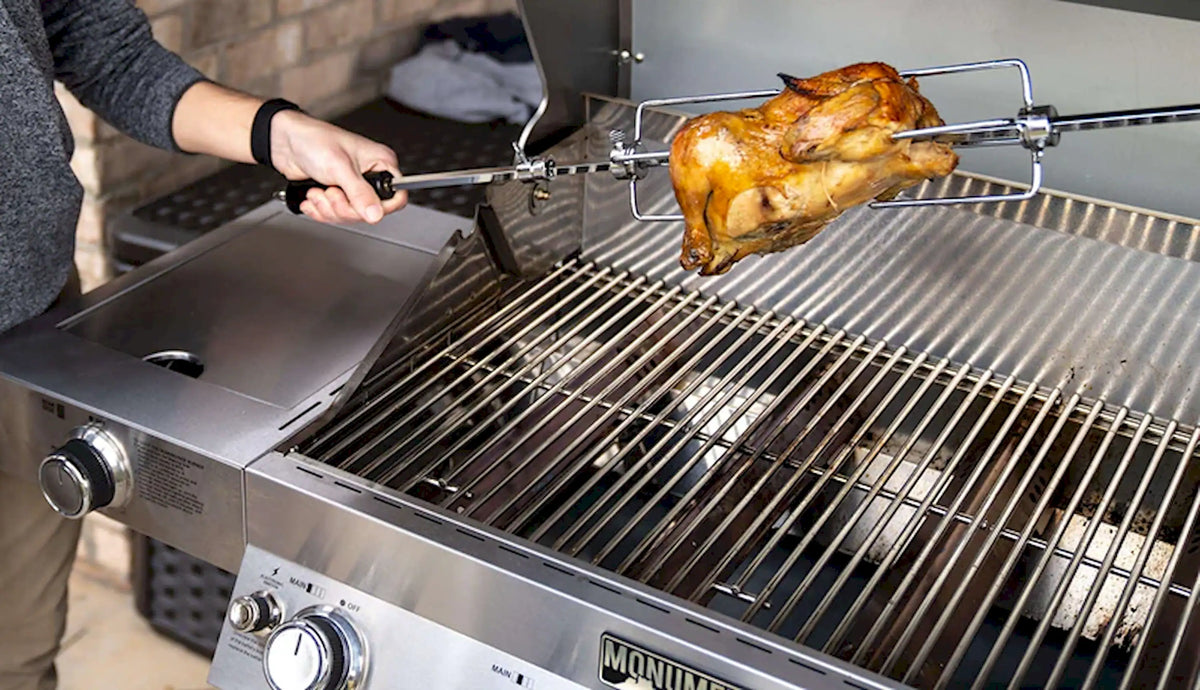 Rotisserie rod with roasted chicken over stainless grill grates being held