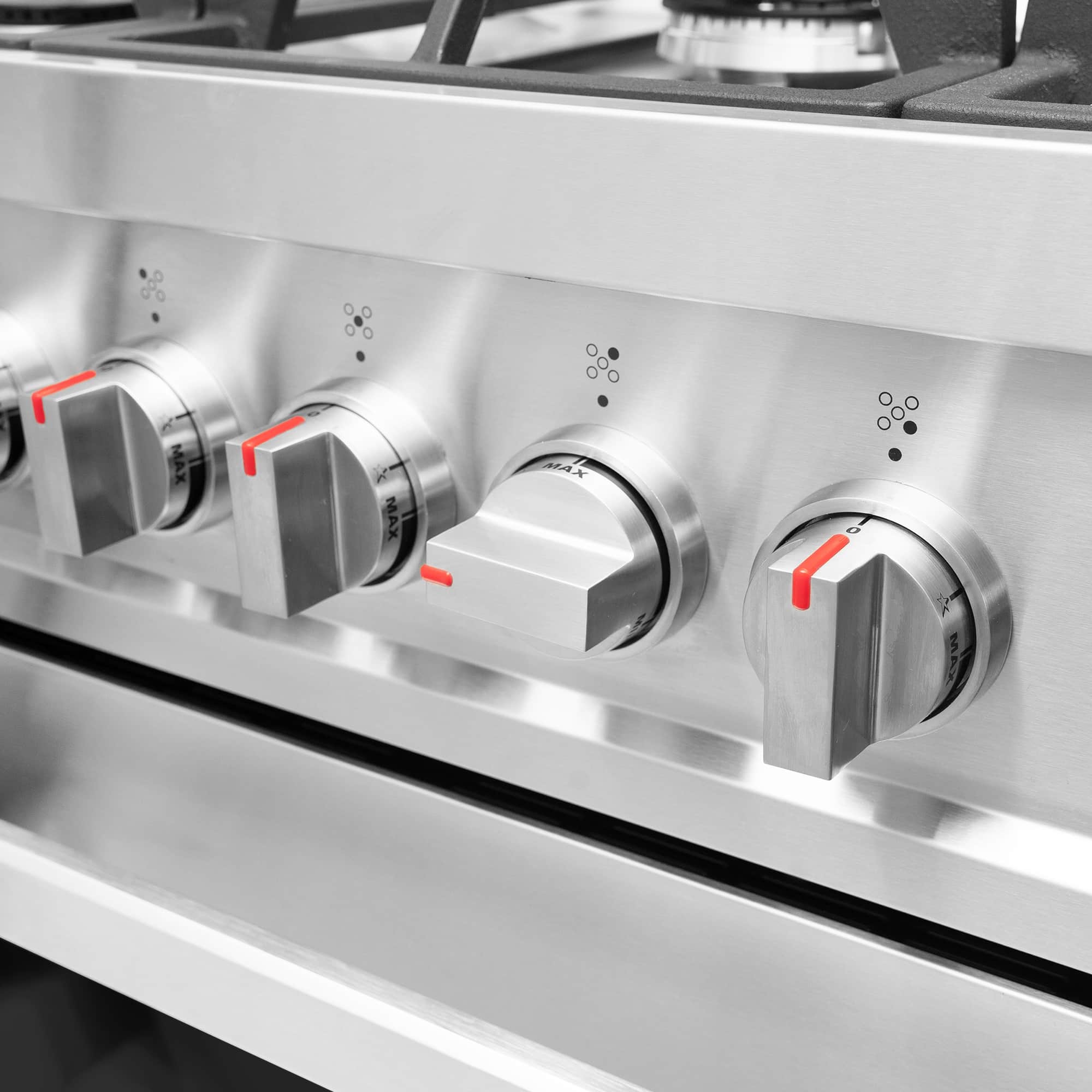 Stainless steel gas range burner knobs with red markings on control panel
