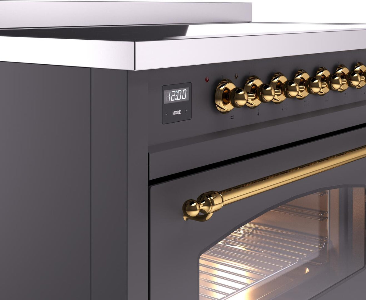 Matte graphite control panel with 12:00 display and brass rotary knobs above oven window.