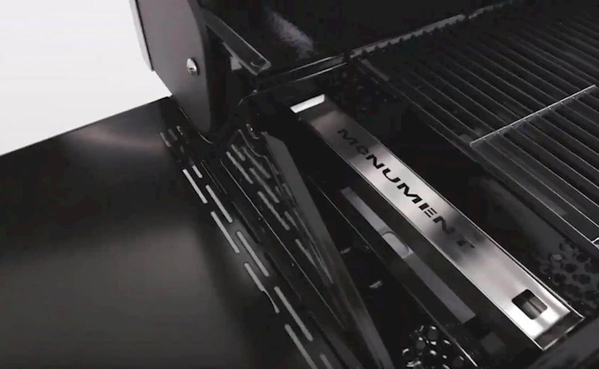 Monument smoker box insert shown on a grill, with vent holes along the side