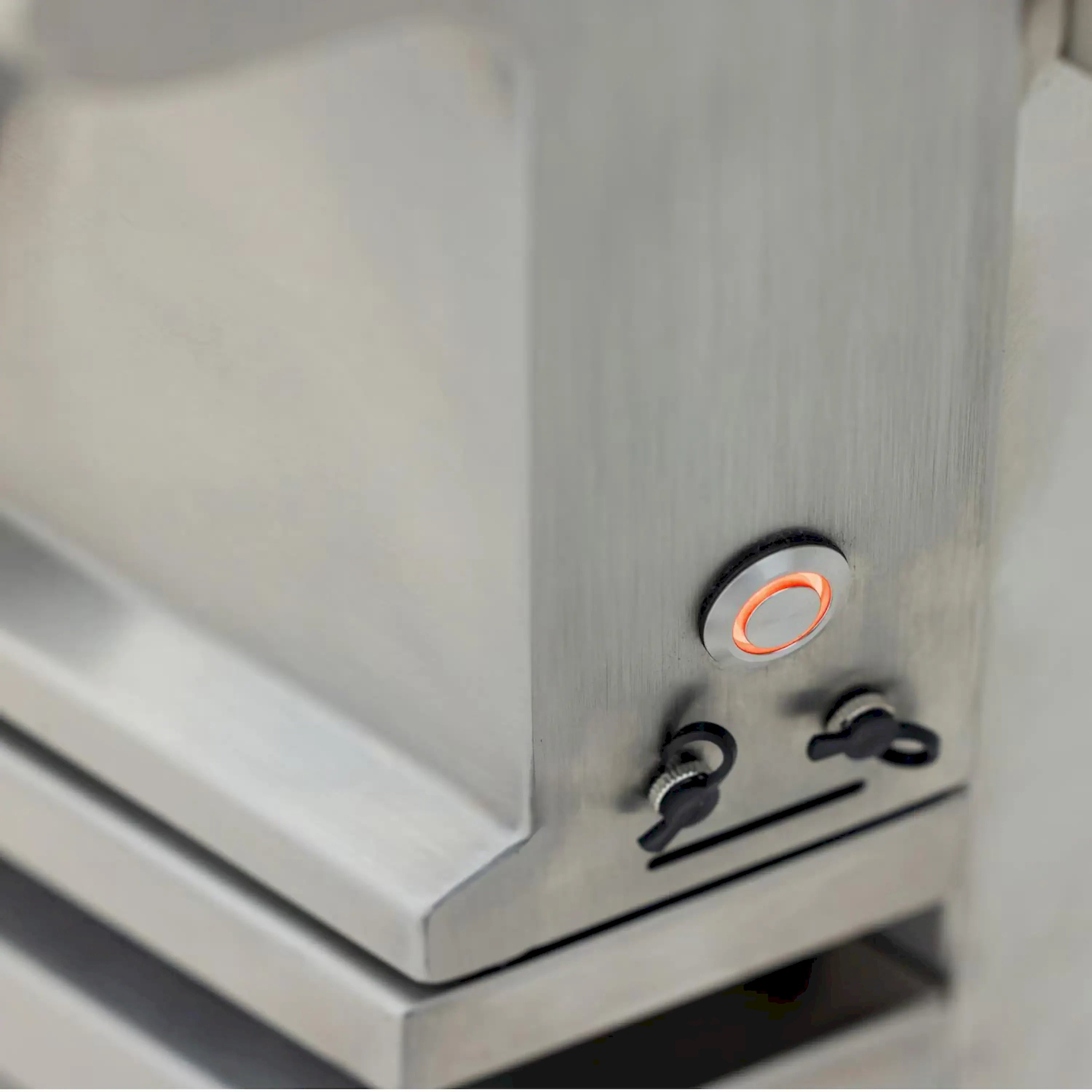 Stainless steel grill control panel with two burner knobs and orange indicator light