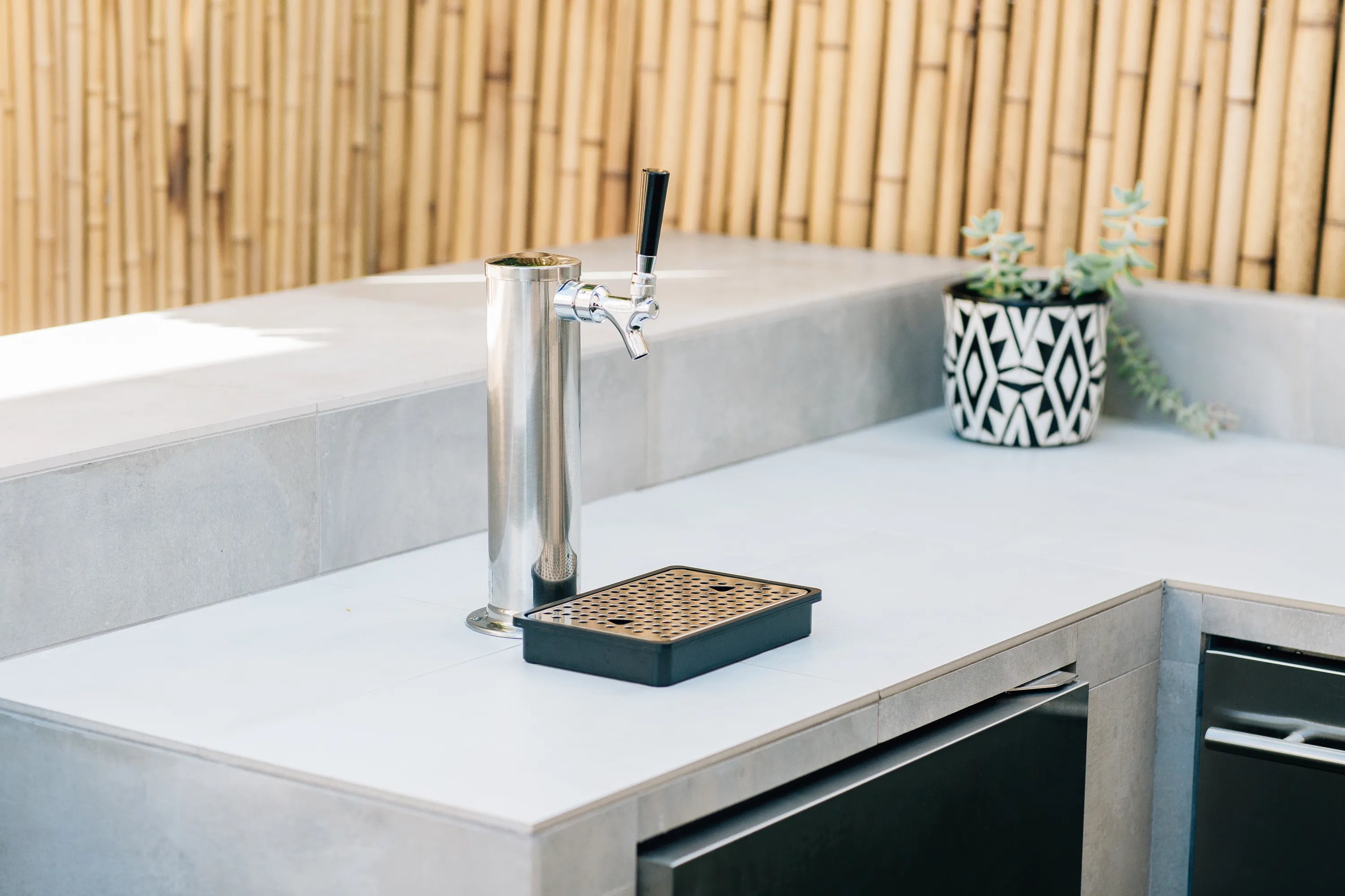 Outdoor kegerator tap faucet on countertop with drip tray and square metal grate