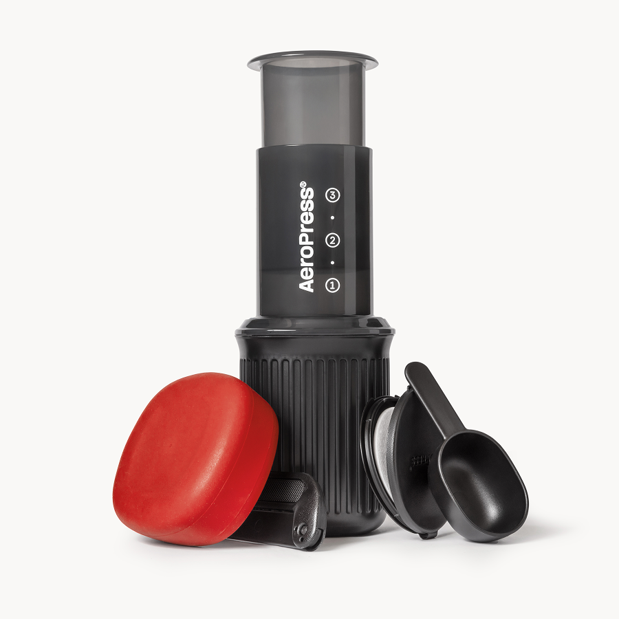 Compact AeroPress coffee maker with red silicone lid and measuring scoop