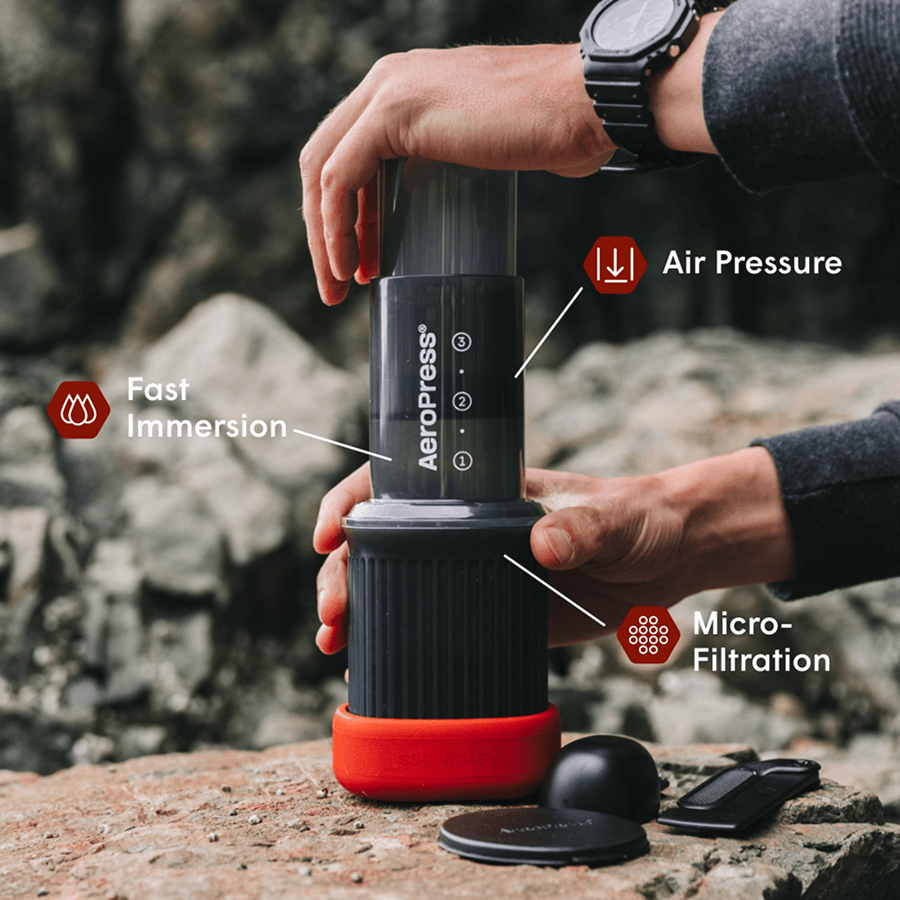 AeroPress coffee maker held over mug with filter and scoop attached