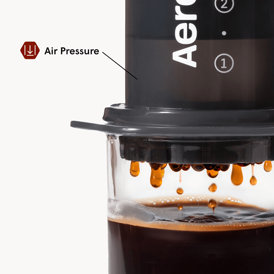Air-pressure brewing chamber releasing hot coffee into a transparent cup
