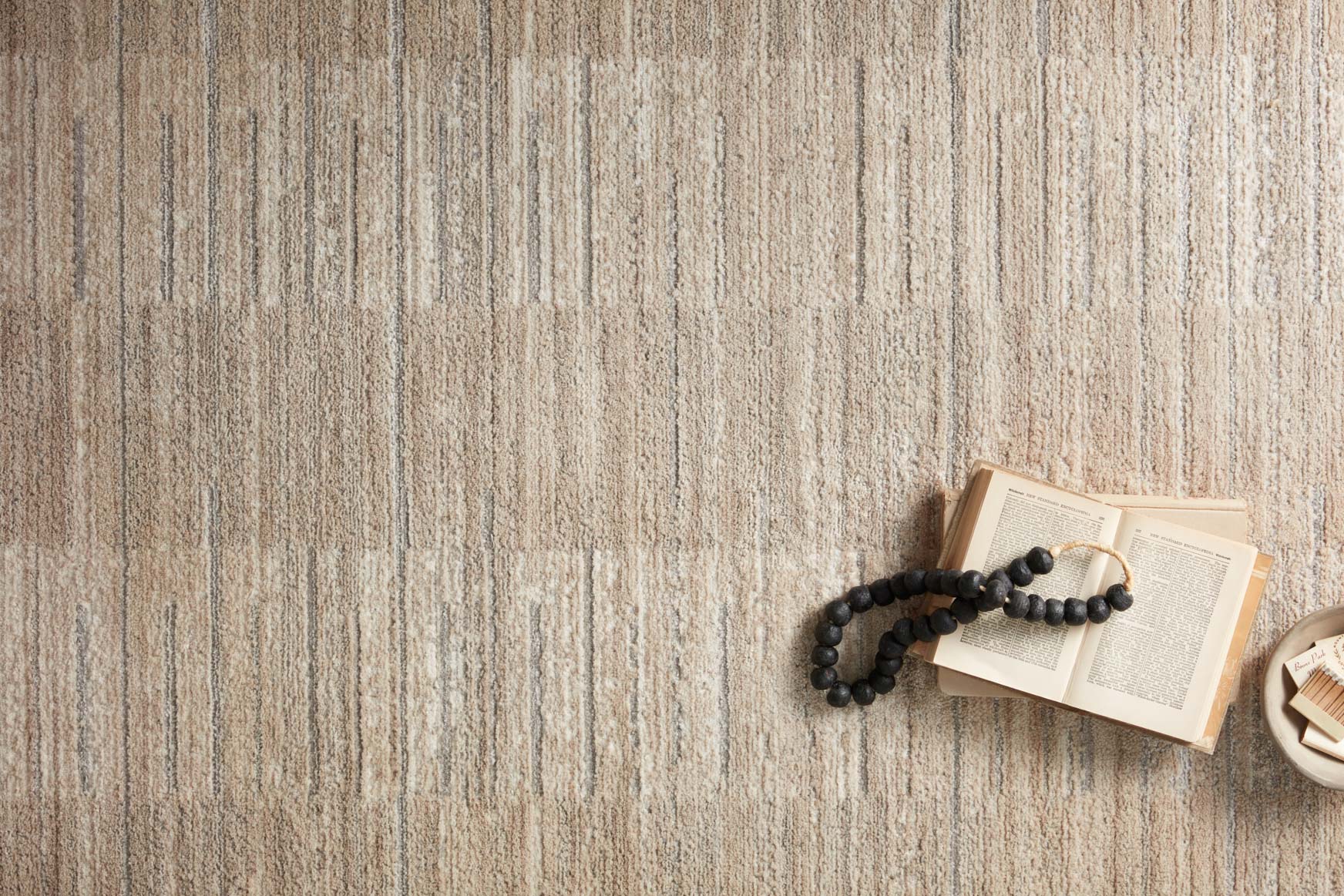 Textured natural and pebble area rug close-up with layered stripe line pattern
