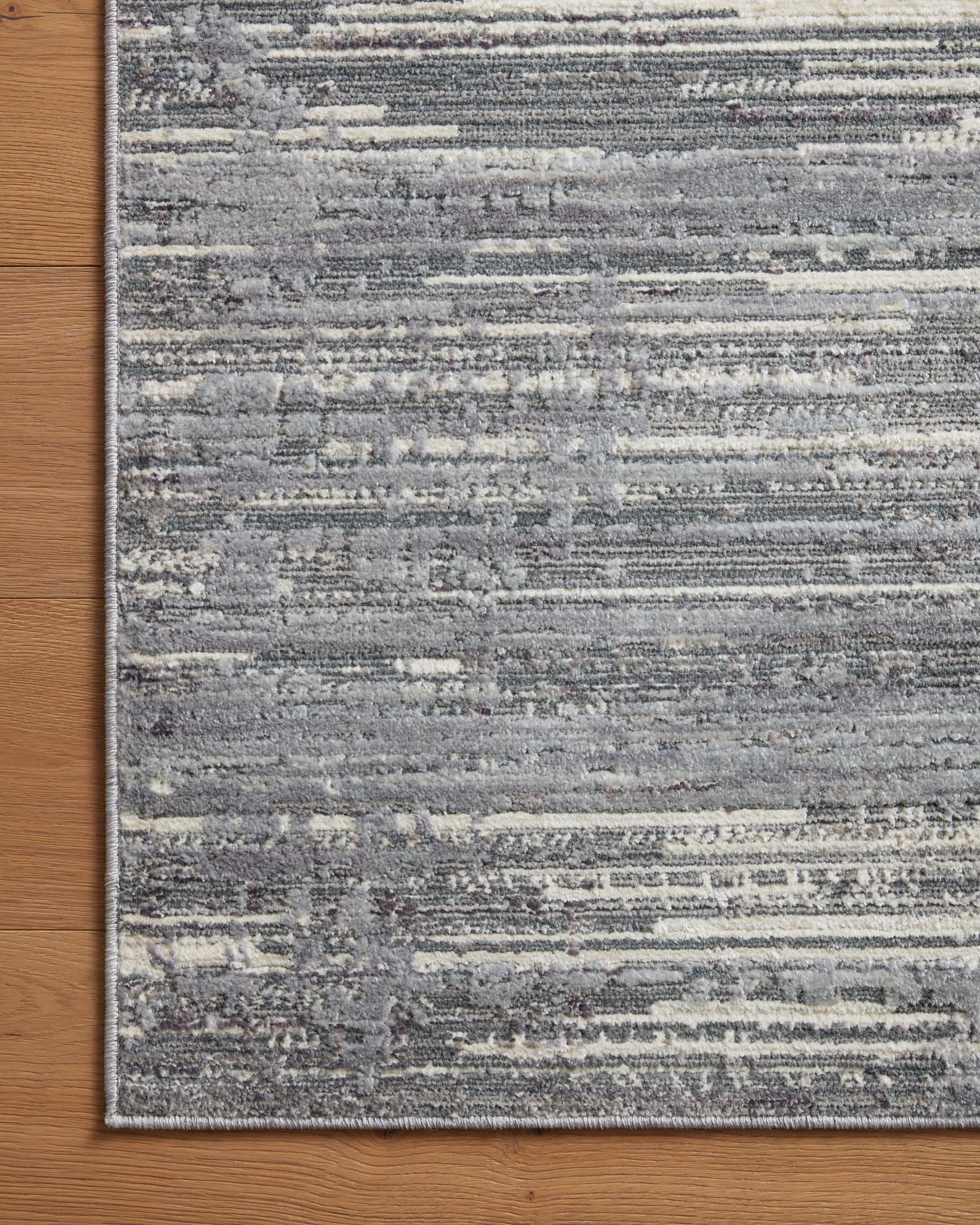 Grey and ivory area rug with distressed horizontal stripes and border, close corner view