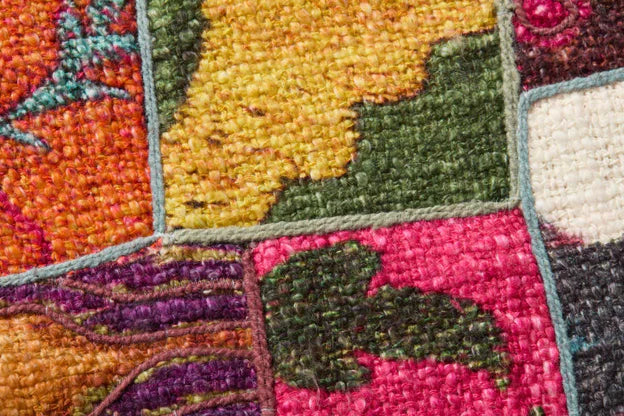 Embroidered rug texture close-up with multicolor fabric blocks and stitched borders