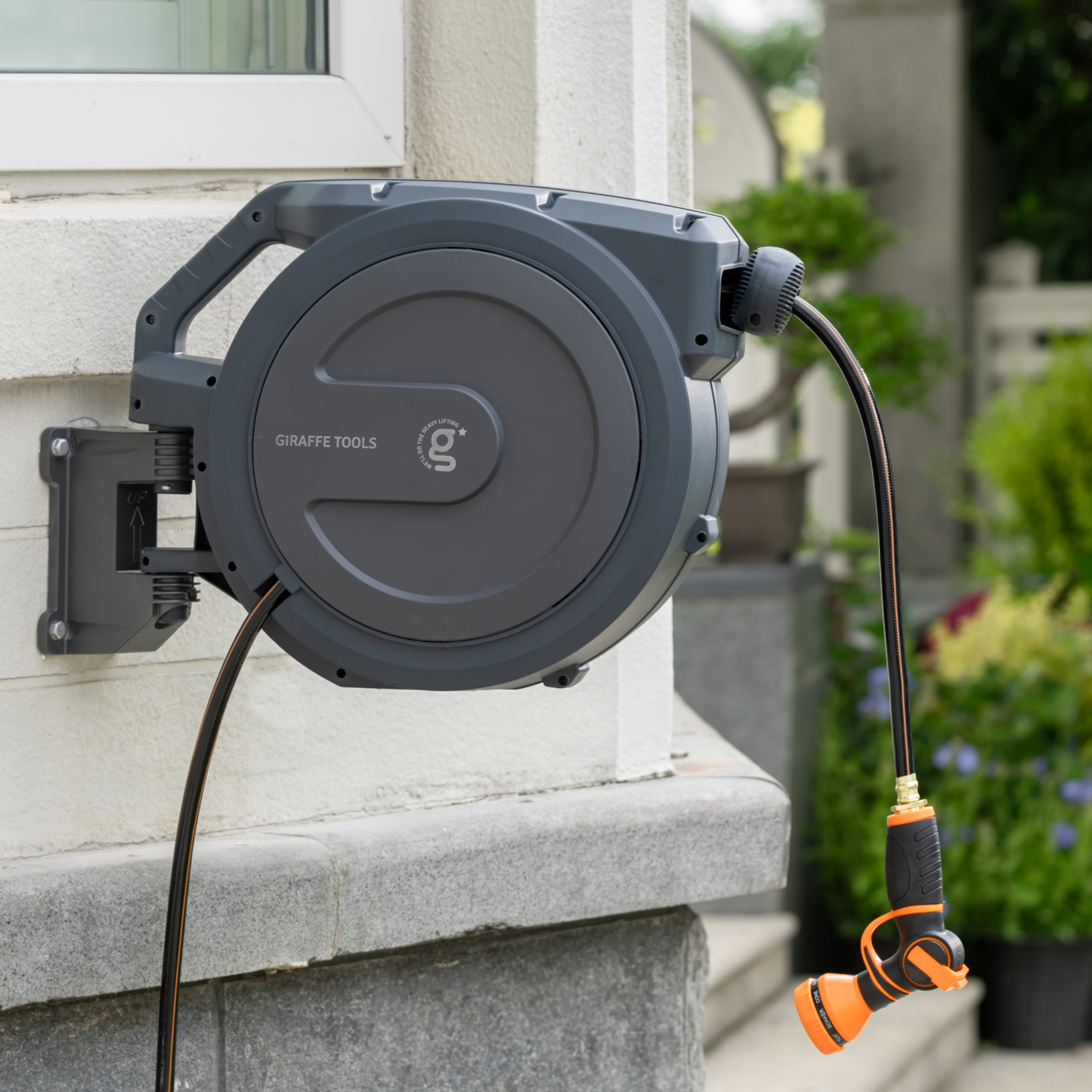 Retractable garden hose reel mounted on wall with dark gray drum and attached hose