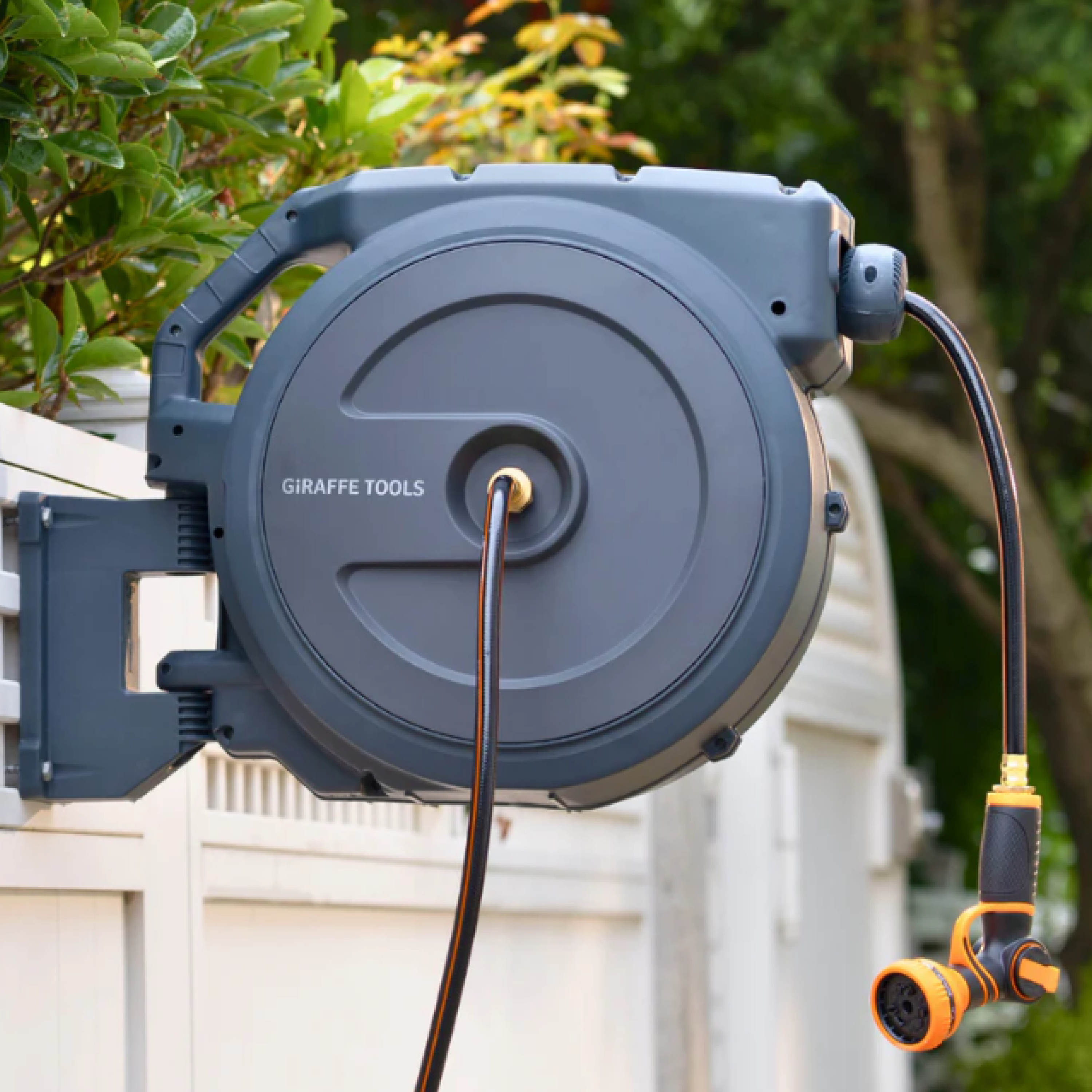 Gray wall-mounted retractable garden hose reel with orange/black nozzle and extended hose