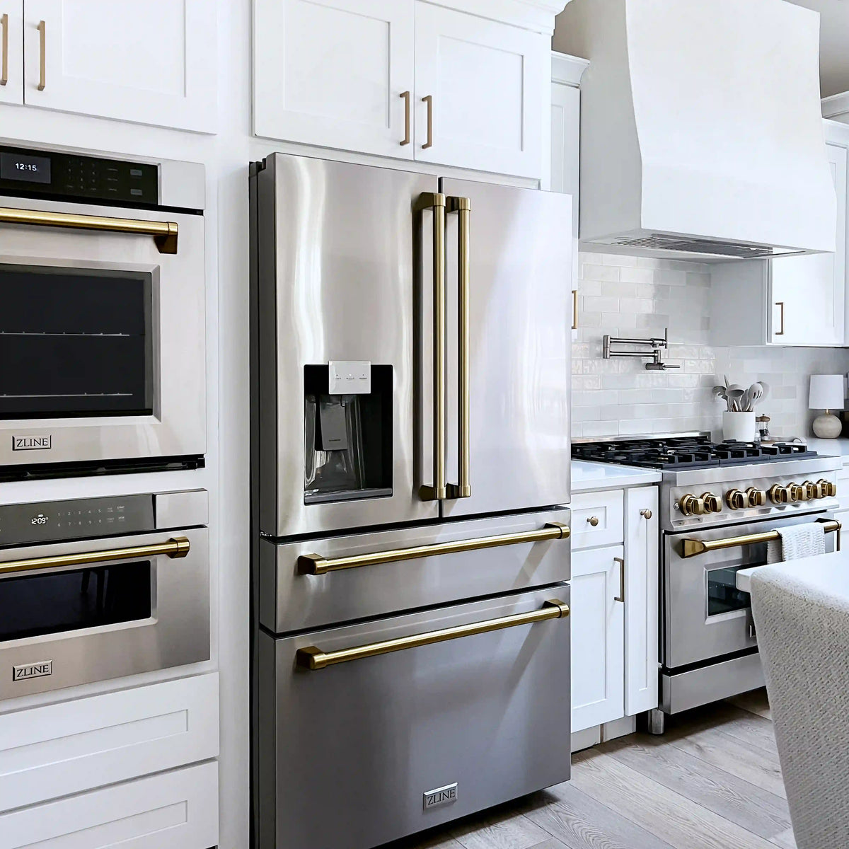 Stainless steel refrigerator with water dispenser beside dual fuel range and ovens