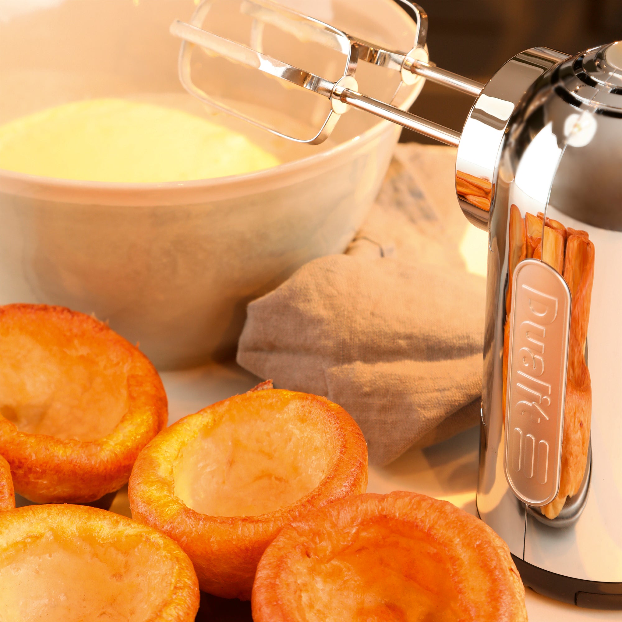 Polished chrome hand mixer with beaters mixing batter in a bowl