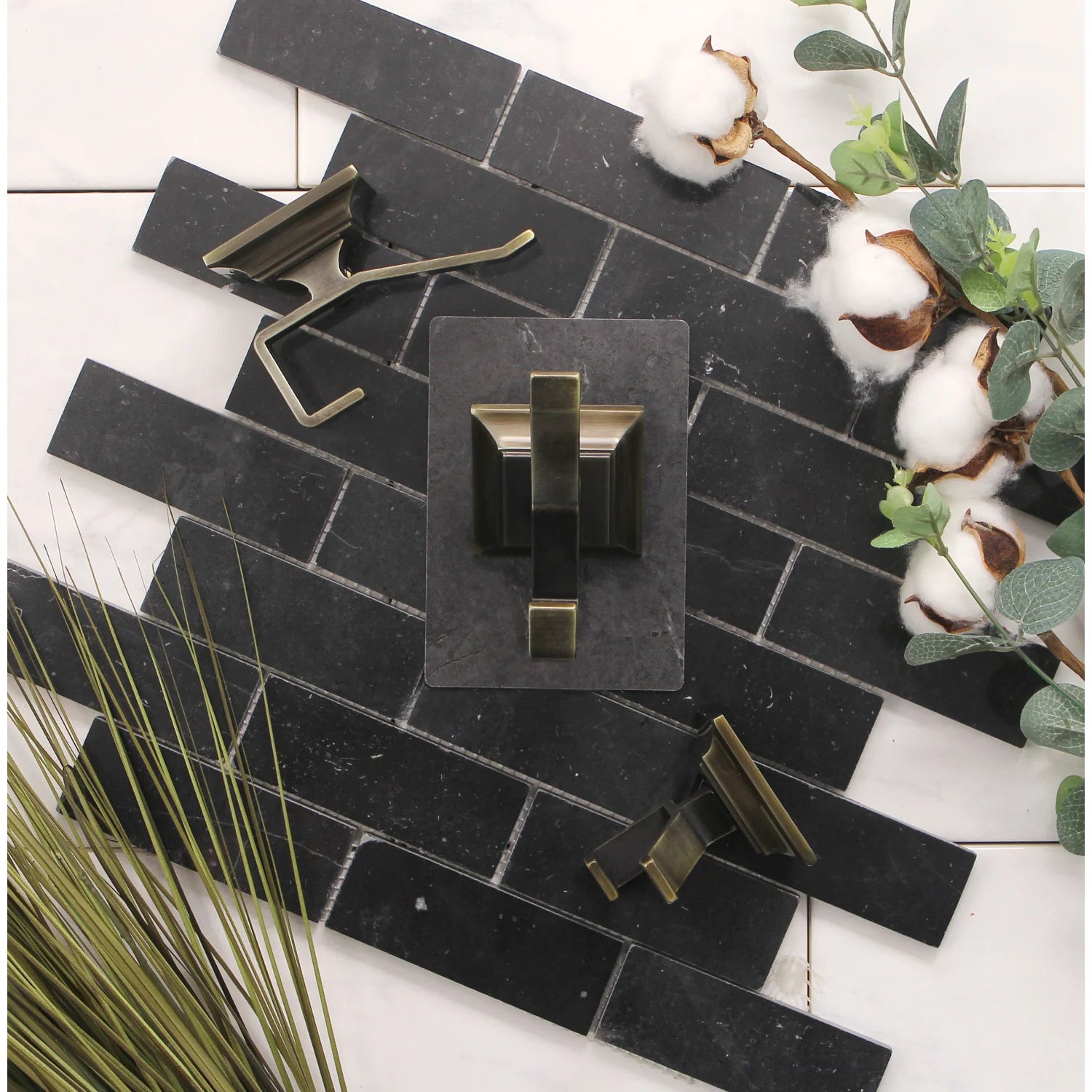 Brass towel robe hooks mounted on black tile, three-piece set