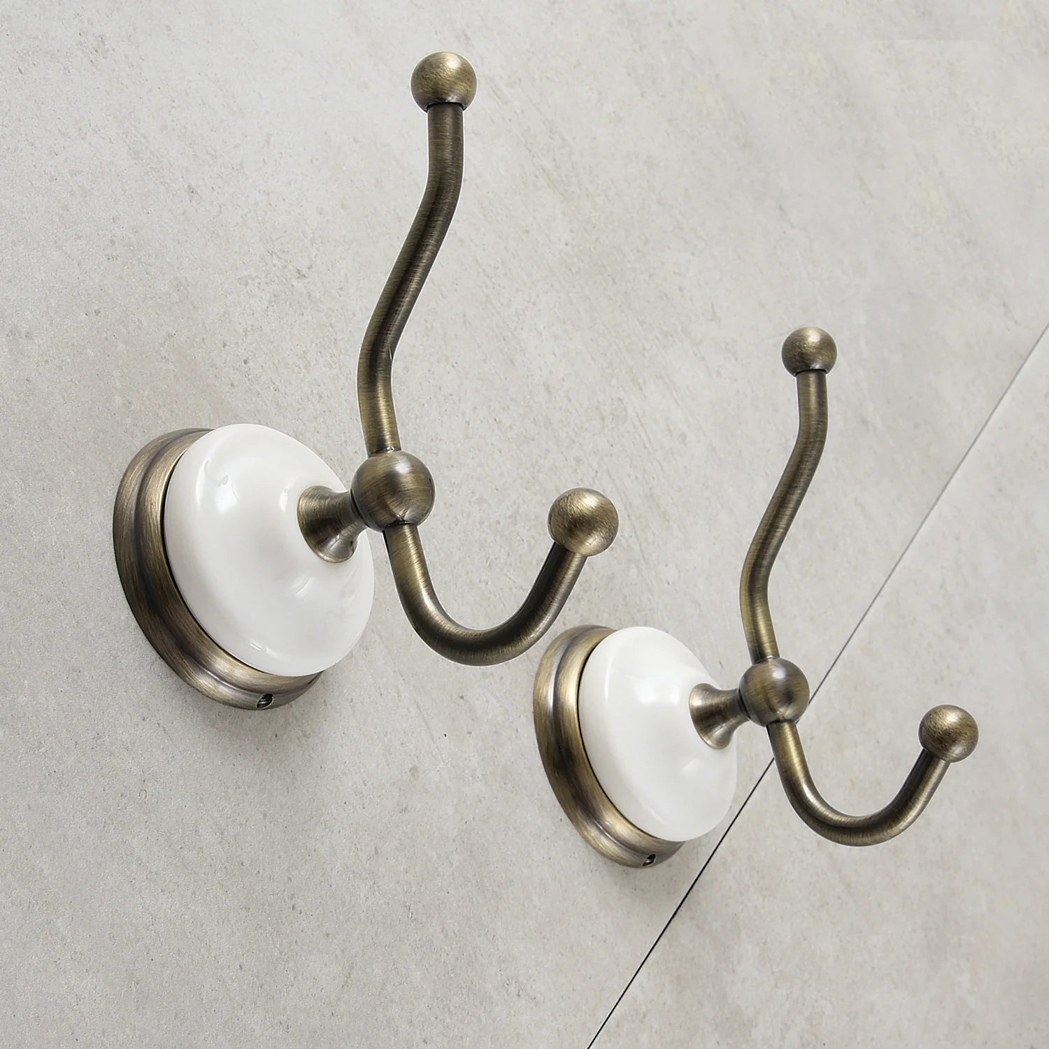 Two Victorian robe hooks with antique brass finish and white ceramic round wall plates