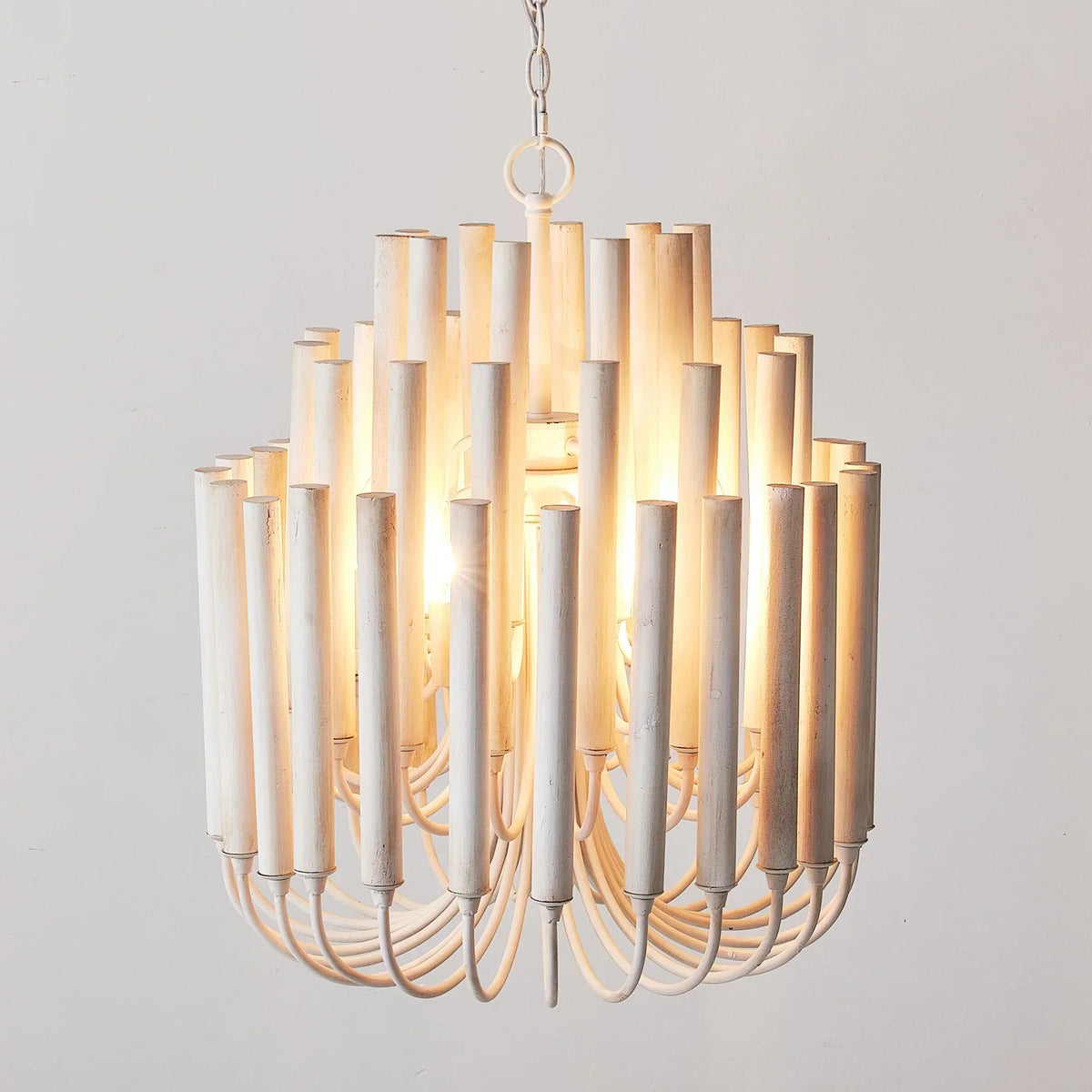 White wooden 5-light chandelier with vertical cylinder shades and warm lit bulbs