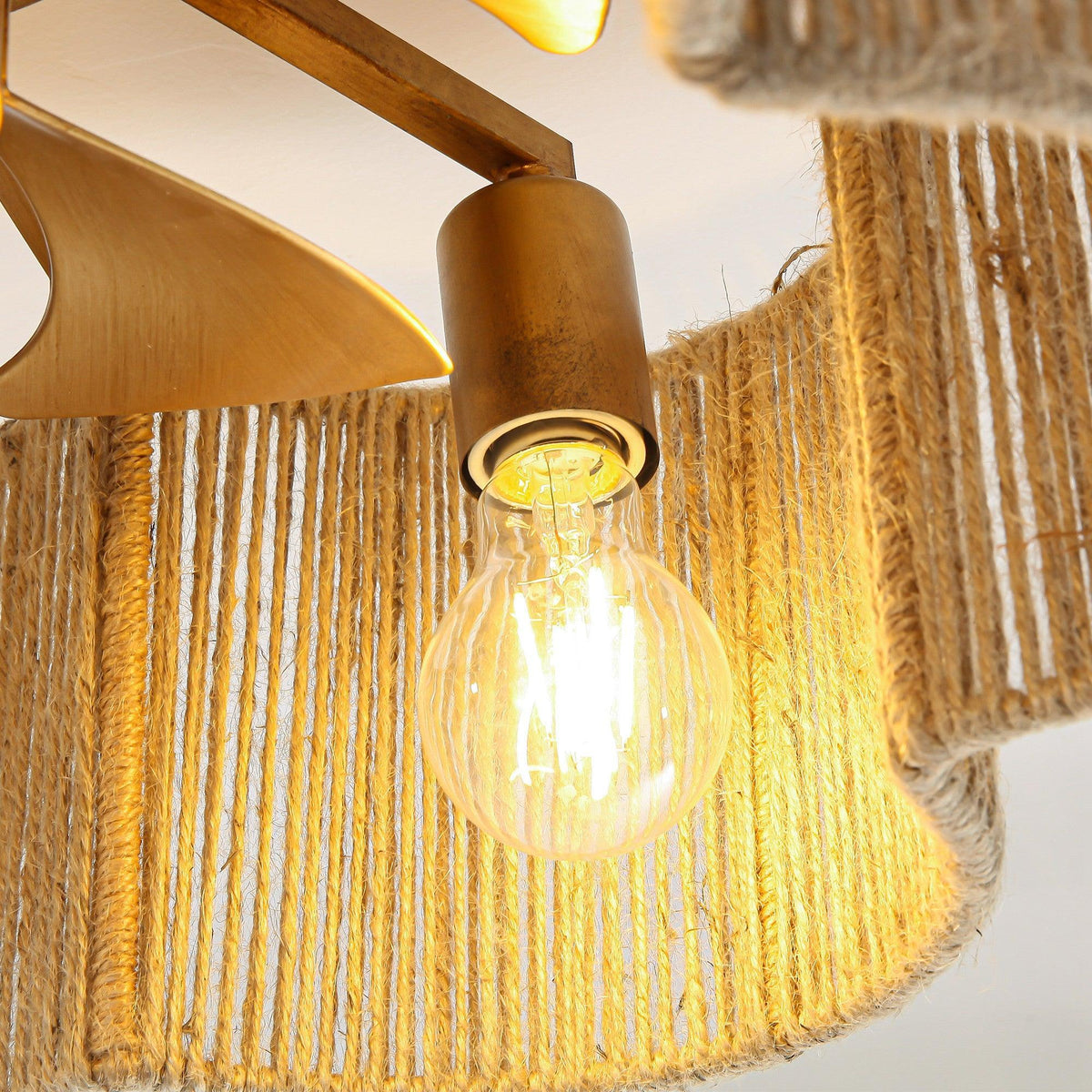 Golden rattan ceiling fan detail: exposed bulb inside braided shade