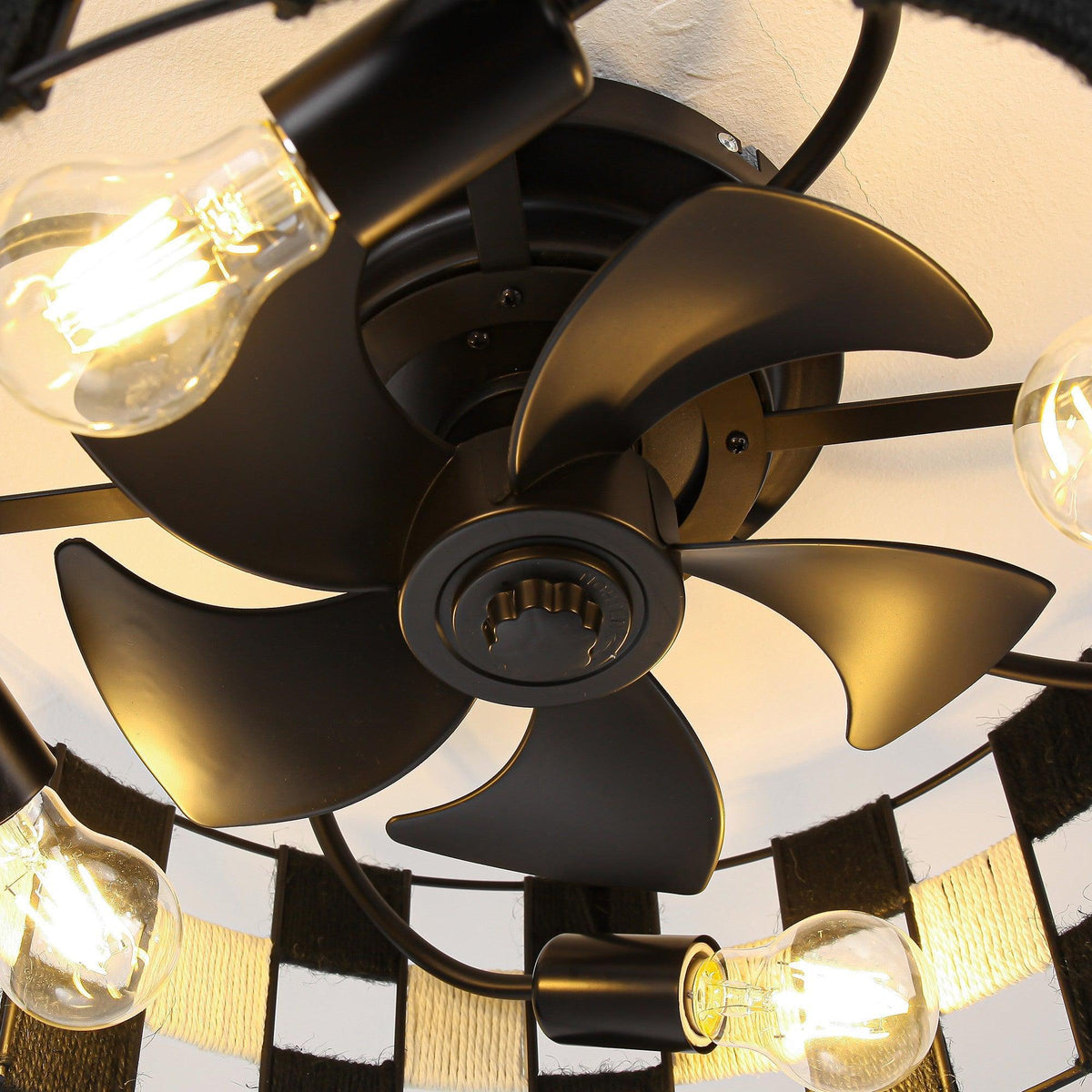 Close-up of black ceiling fan blades with lit bulbs and metal center hub