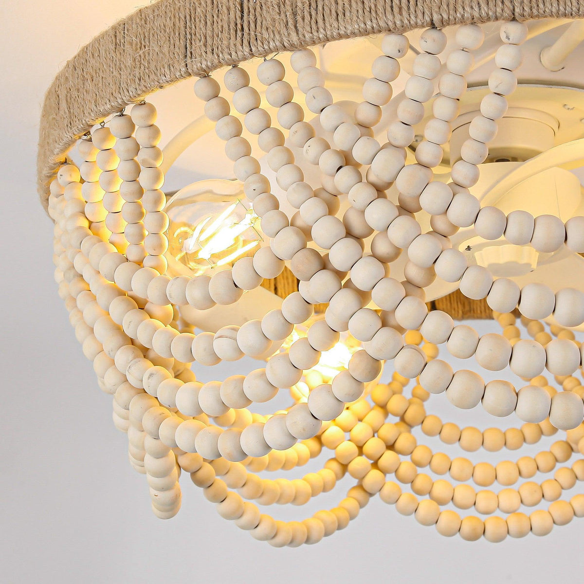Detail view of the wood bead lampshade around a white flush-mount ceiling fan