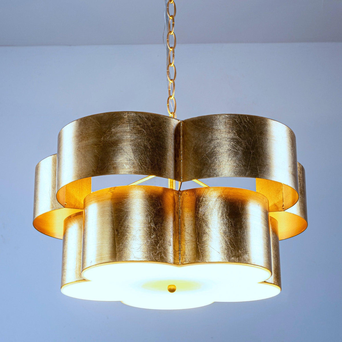 Golden drum island pendant with tiered cylindrical shade panels and warm light