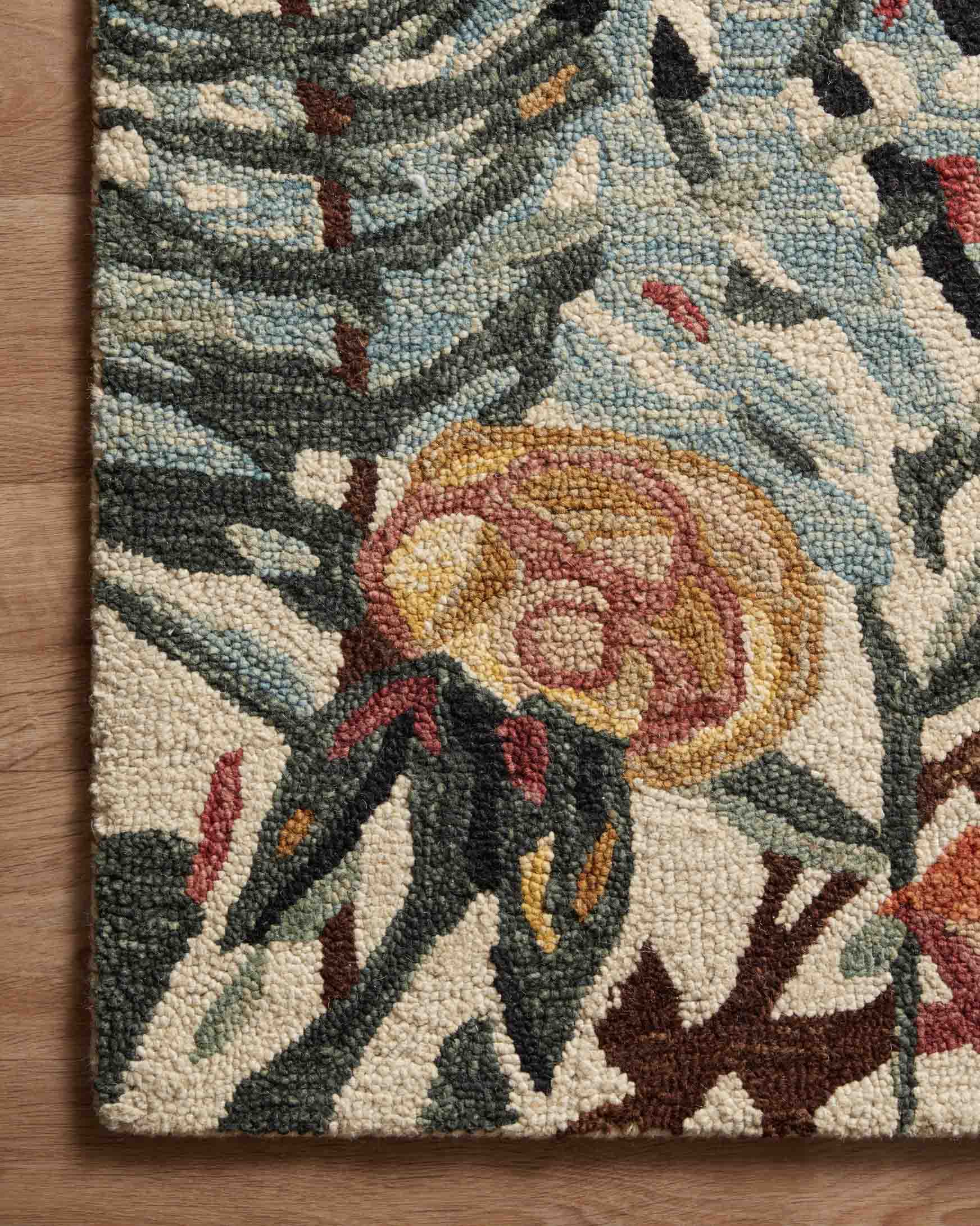 Corner of floral accent rug with ivory pile and teal, black, and red rose details.
