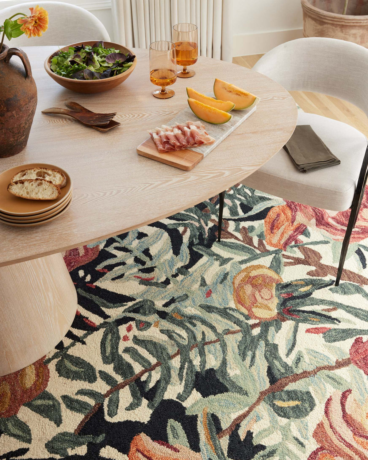 Round accent rug with dense multicolor botanical pattern in ivory, teal, and rust tones
