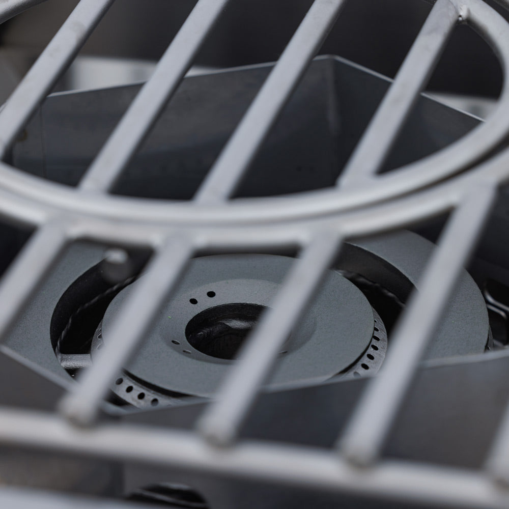 Natural gas burner head with metal grate and circular burner ports