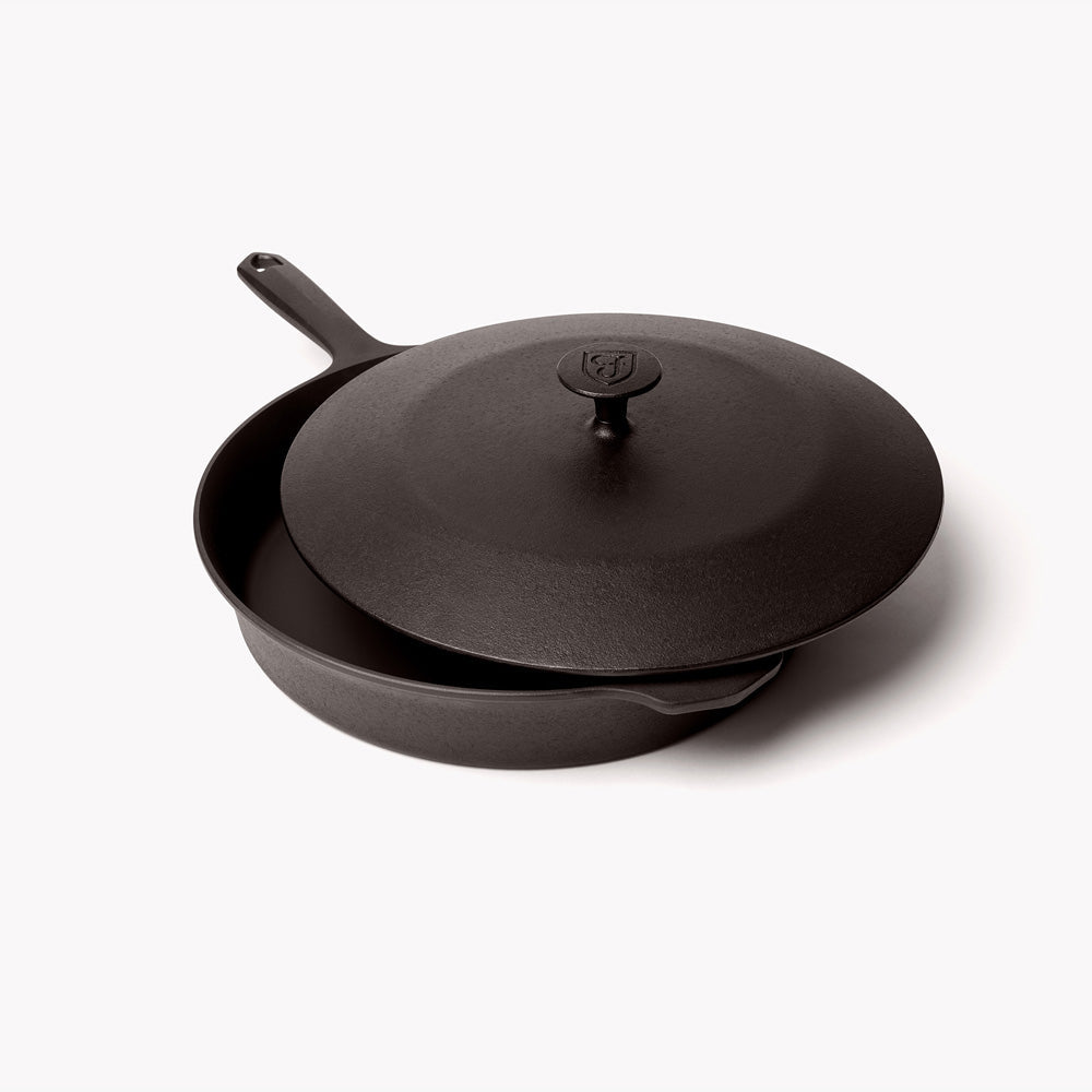 Cast iron skillet with matching lid, dark charcoal finish, side handle visible
