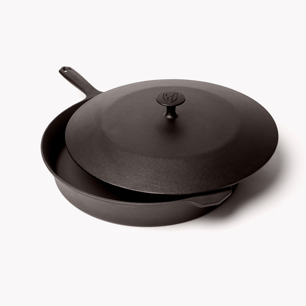 Dark cast iron skillet with matching lid and central knob