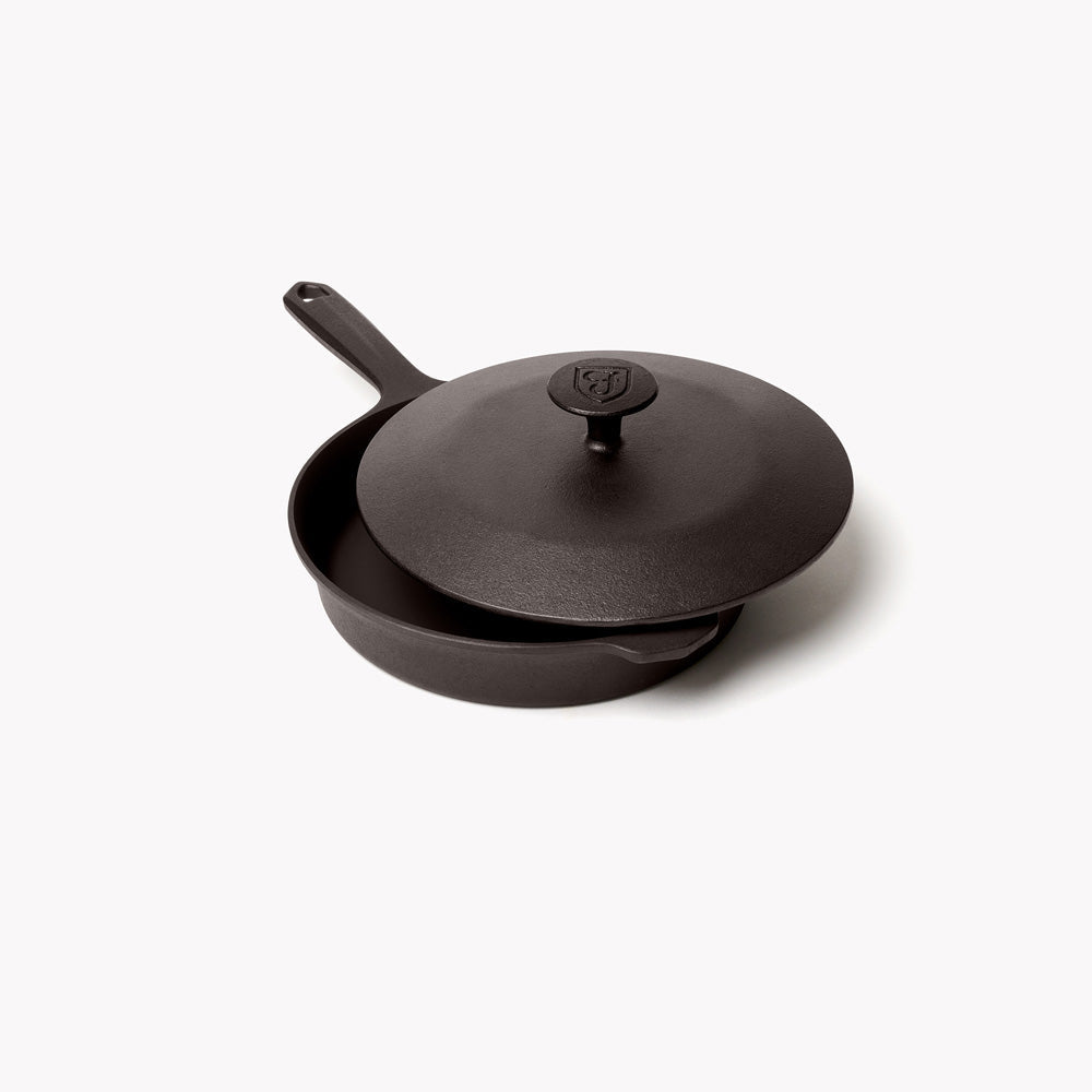 Black cast-iron skillet with lid, long handle, and knob on top