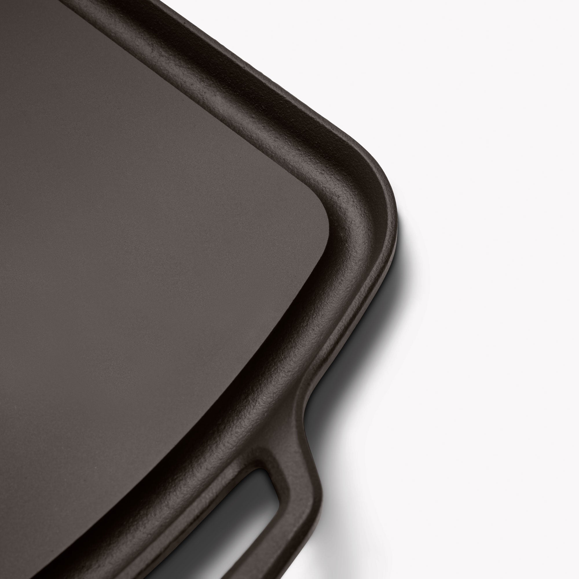 Close-up of dark cast iron griddle rim and handle loop