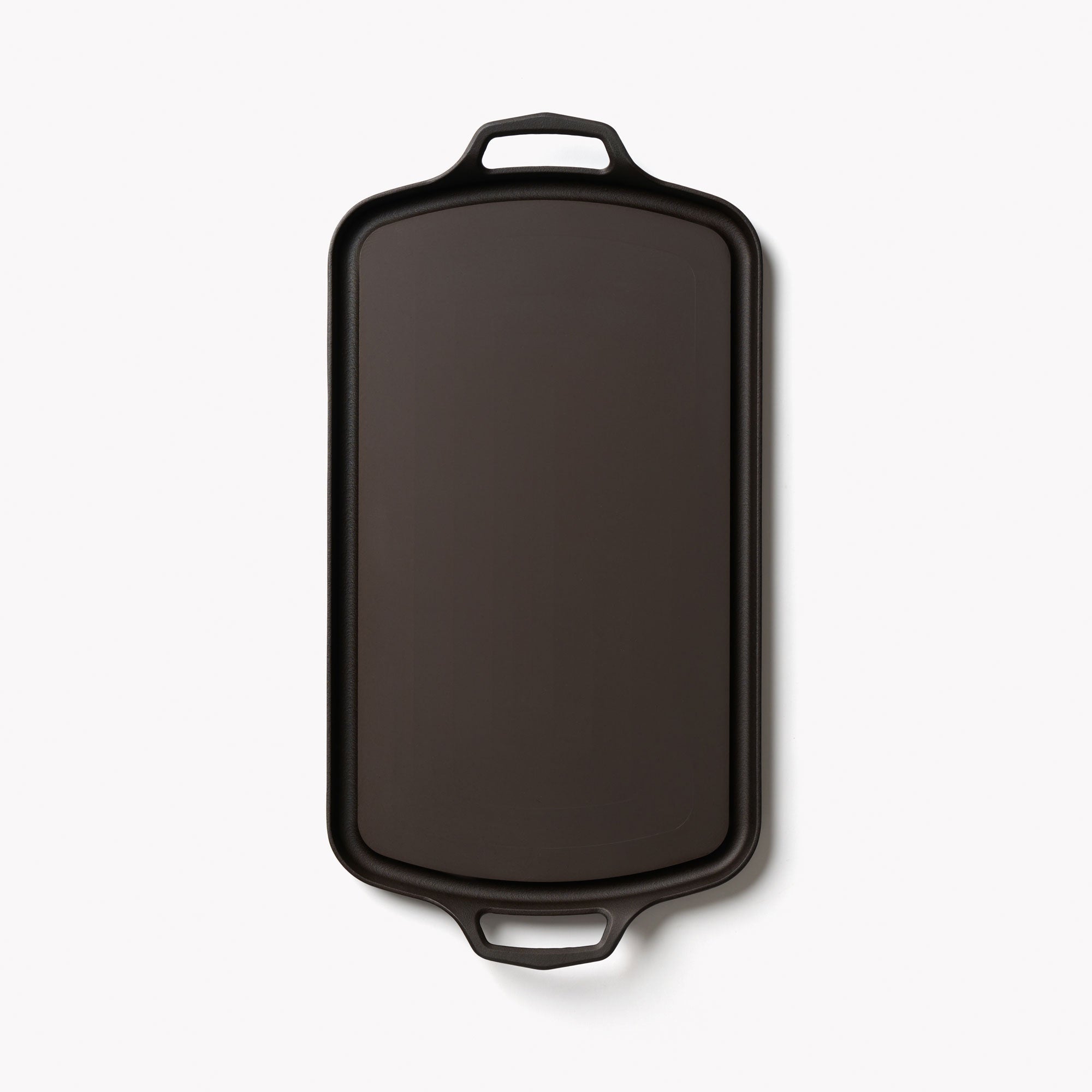Cast iron griddle with top handle loop and contoured body, dark finish
