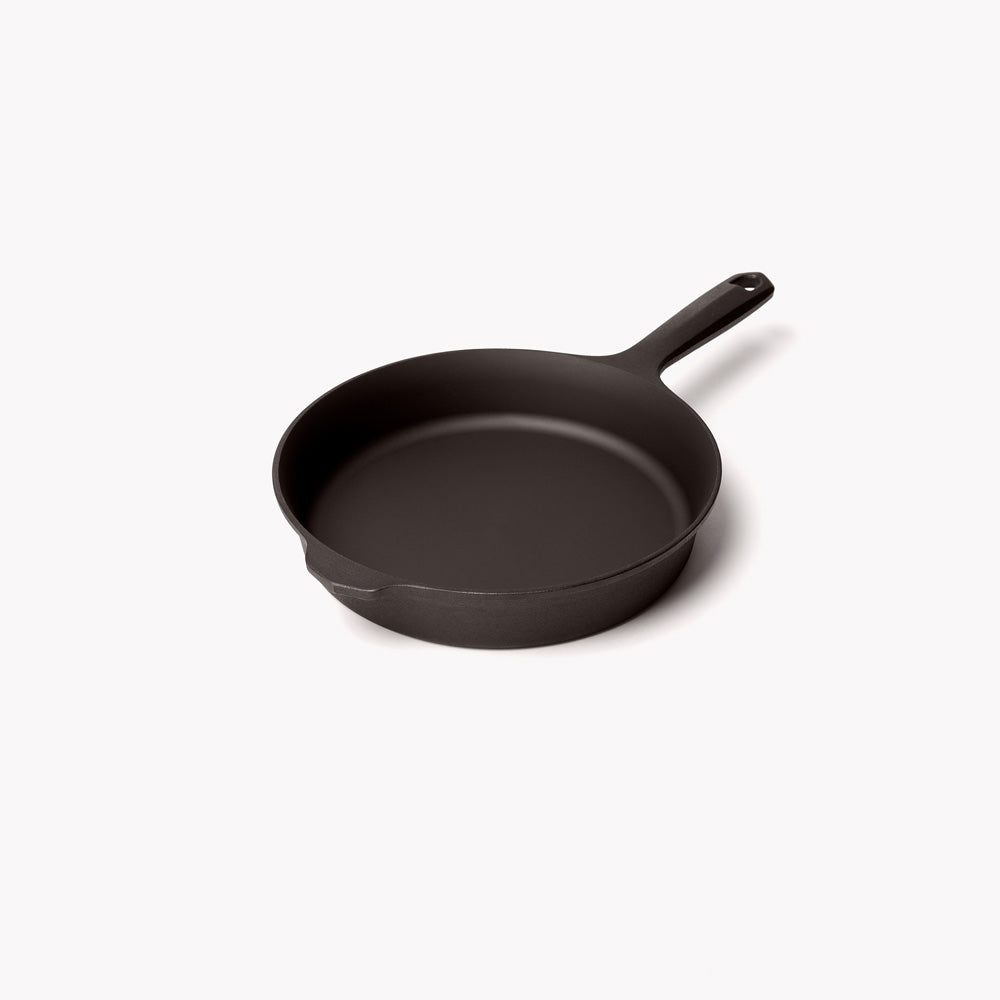Black cast iron skillet with short side handle and shallow bowl