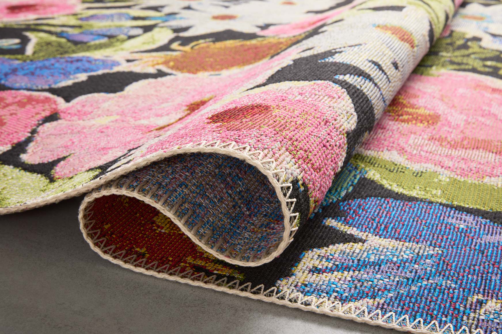 Rolled edge of botanical runner rug with multicolor floral weave and stitched trim