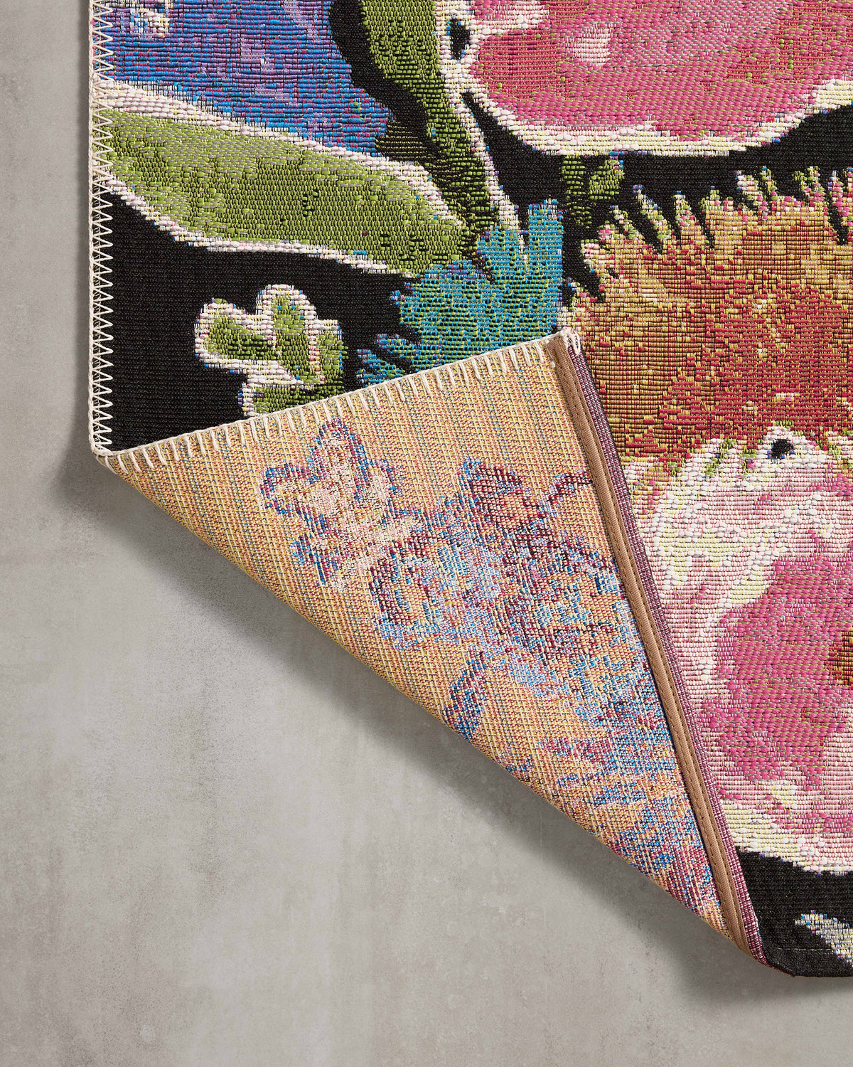 Folded corner of botanical rug showing woven texture and multicolor flowers