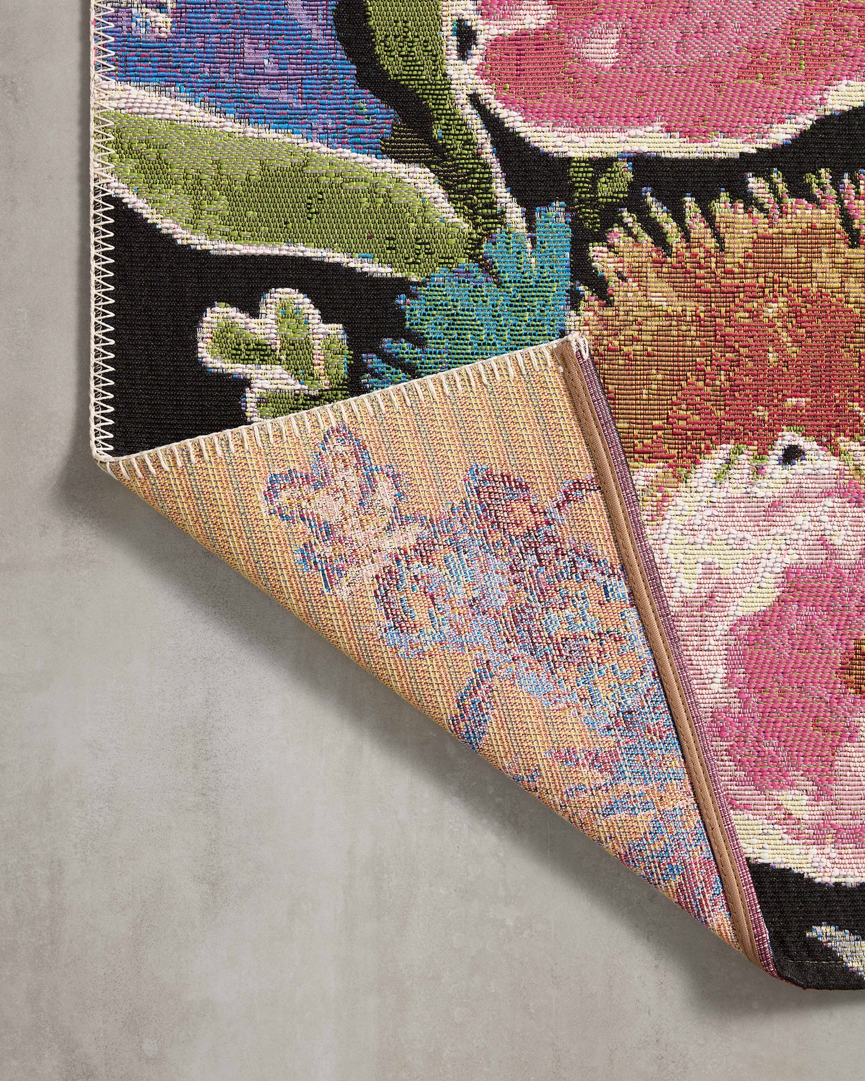 Rolled black floral runner rug corner with multicolor blooms and zigzag edge